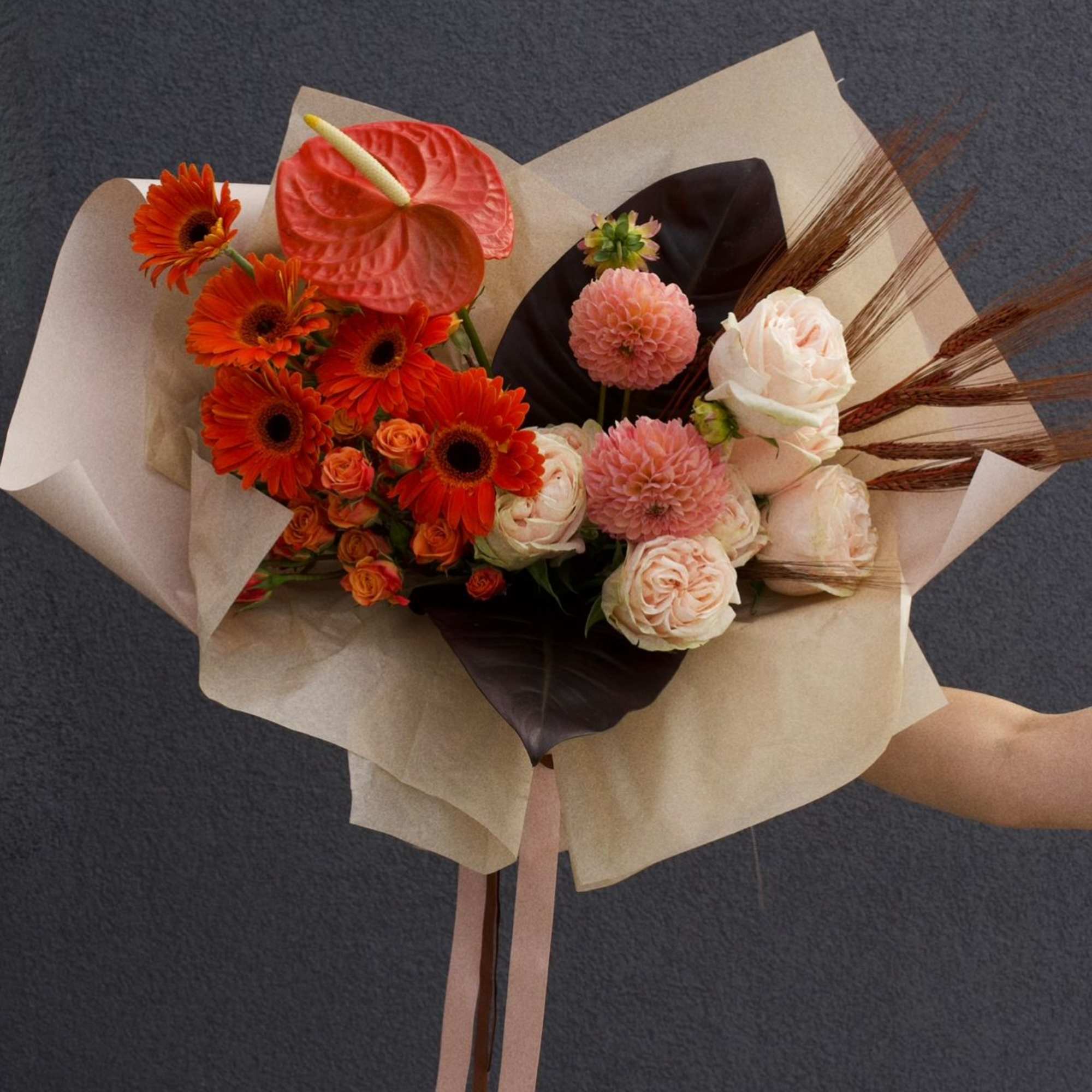 A warm harmony of orange, soft pink and brown blooms, this bouquet