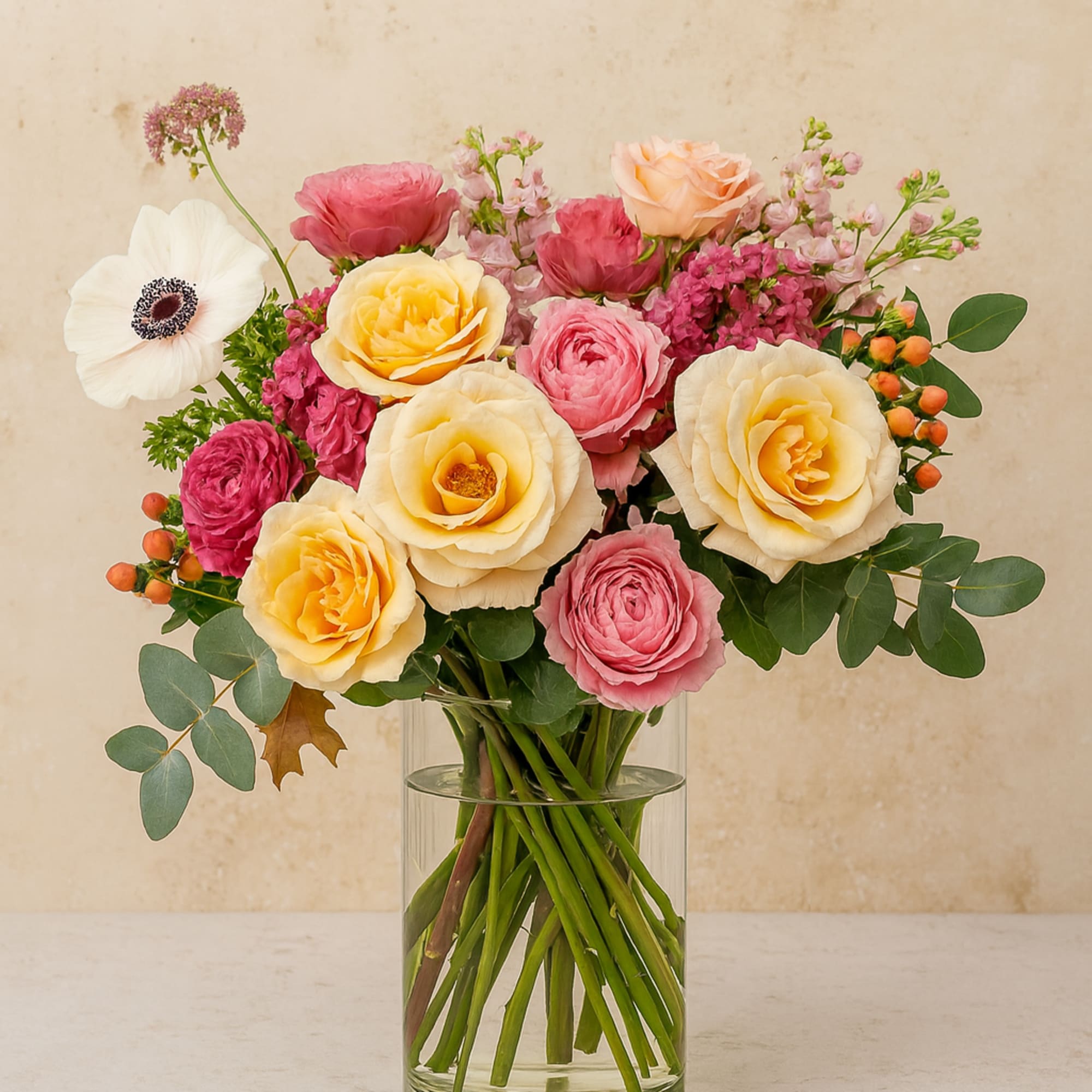 A graceful blend of blush-pink and peach garden roses, vibrant ranunculus, a