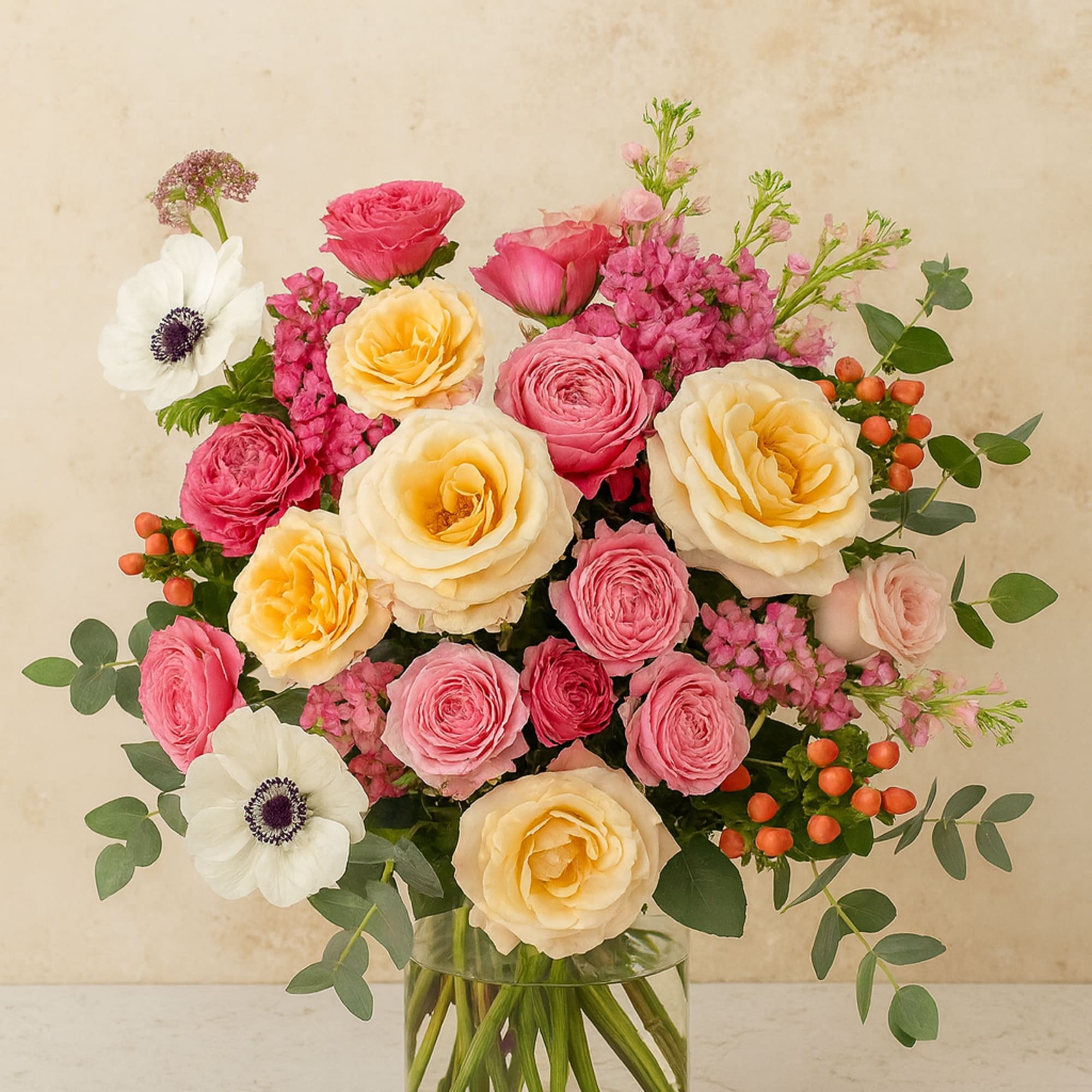 A graceful blend of blush-pink and peach garden roses, vibrant ranunculus, a