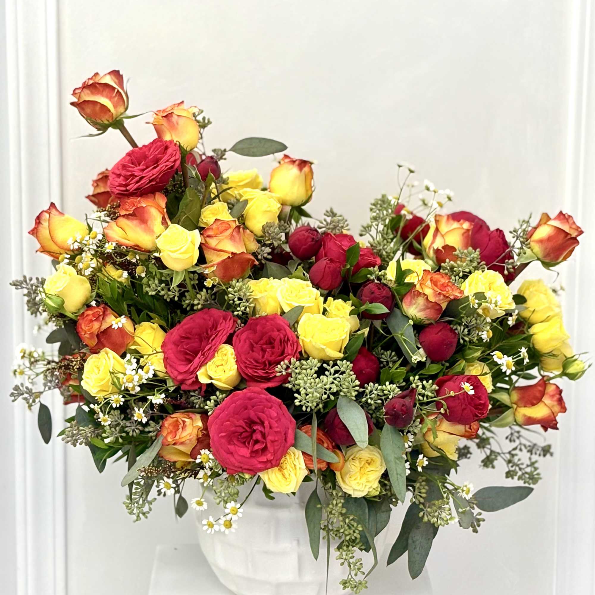 A harmonious mix of warm-hued roses and fresh greenery, perfect for brightening