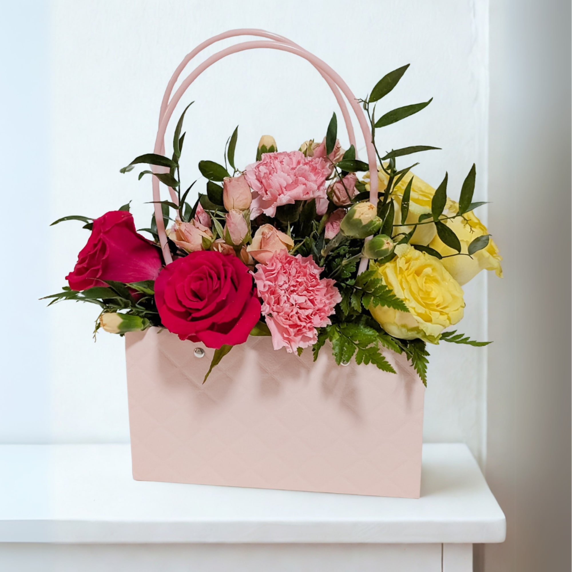 A stylish arrangement designed in a soft blush handbag container, featuring a
