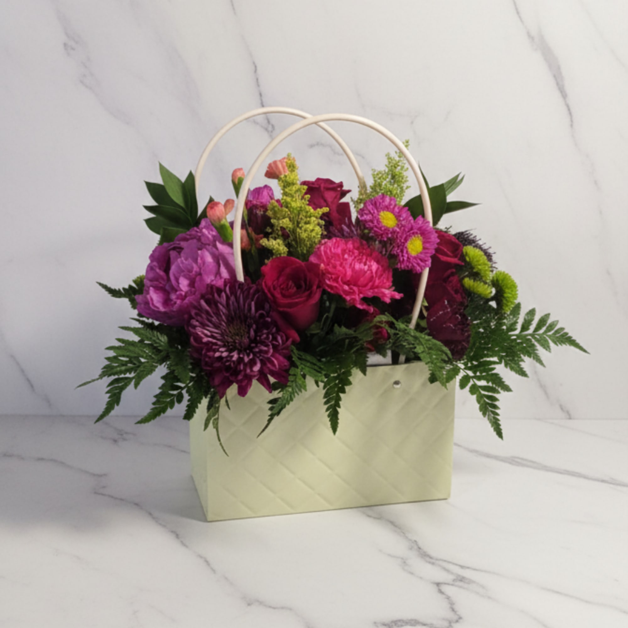 A stylish arrangement designed in a soft blush handbag container, featuring a