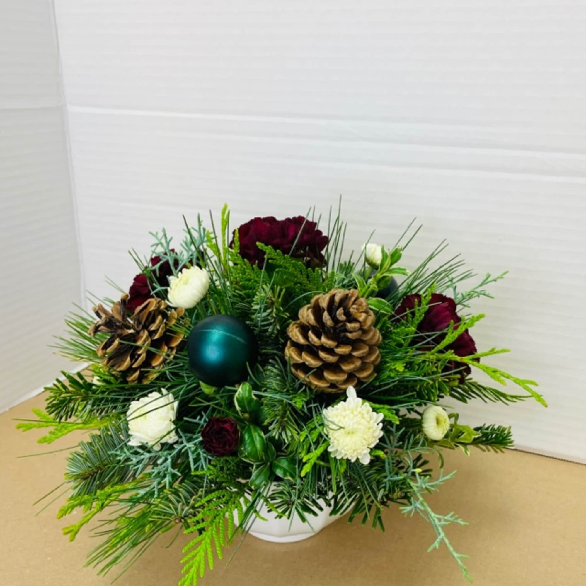 Winter greens and seasonal blooms with festive accents designed in a low