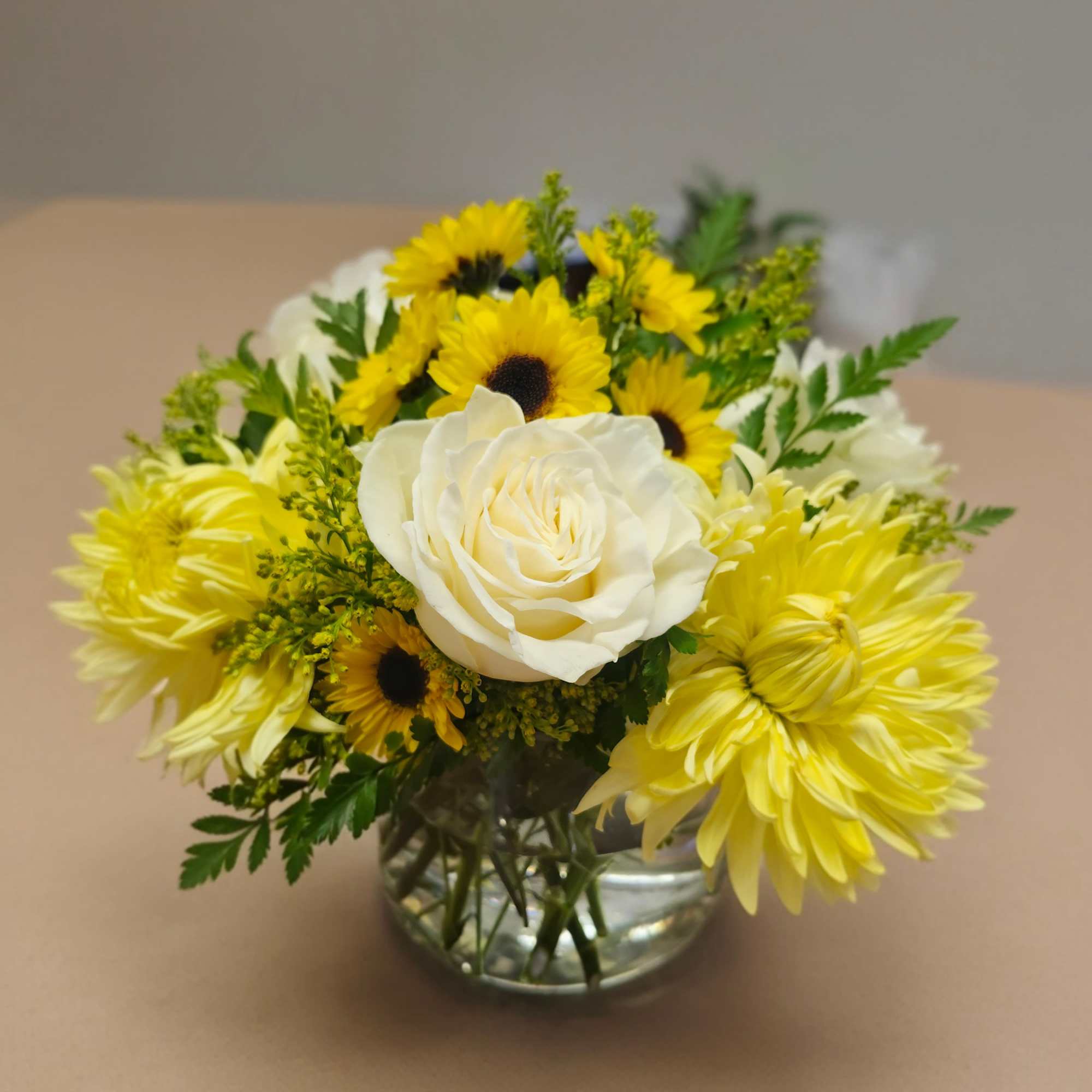 Bright and comforting, this cheerful arrangement blends soft white roses with sunny