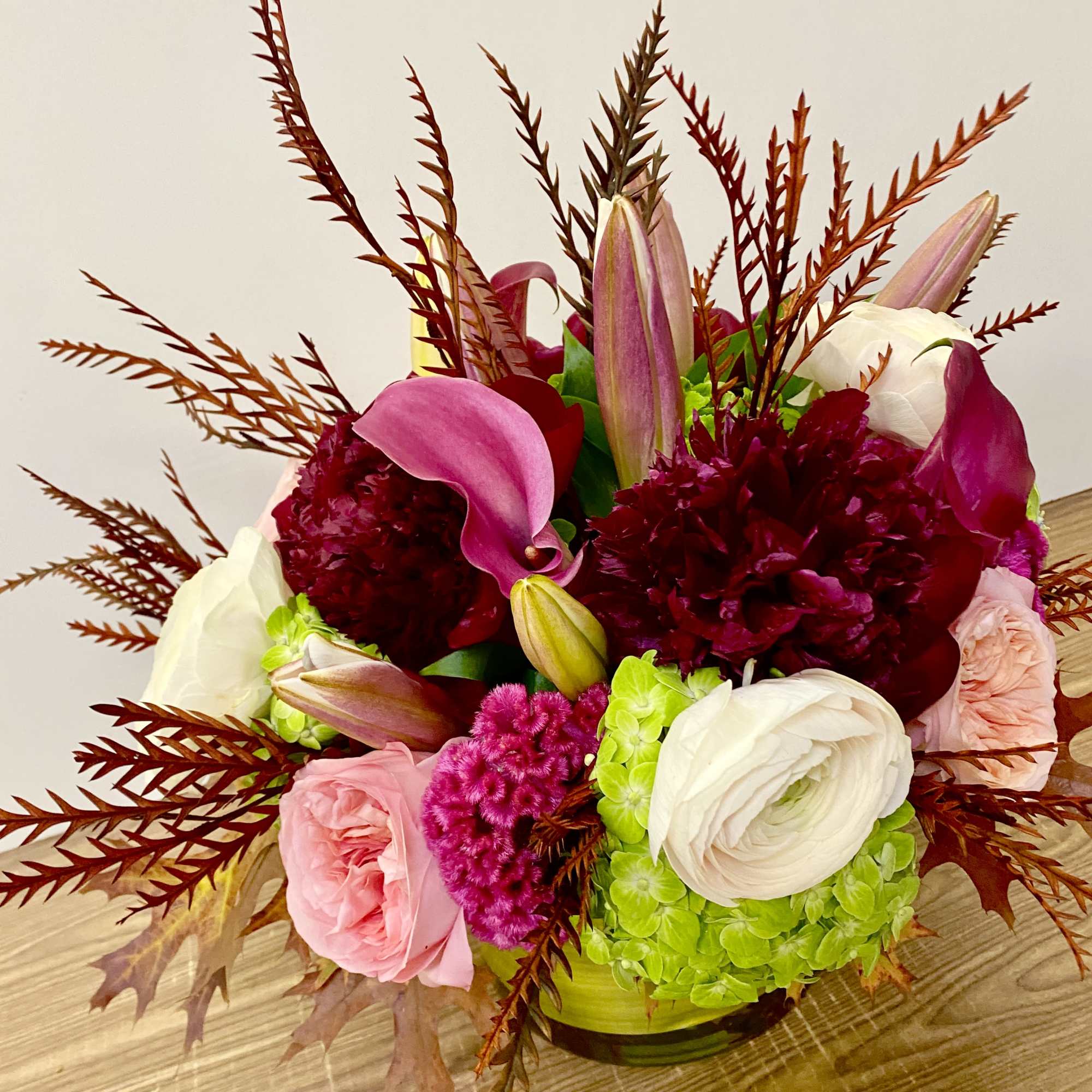 In a glass vasr combinations of pink roses white ranunculus and no