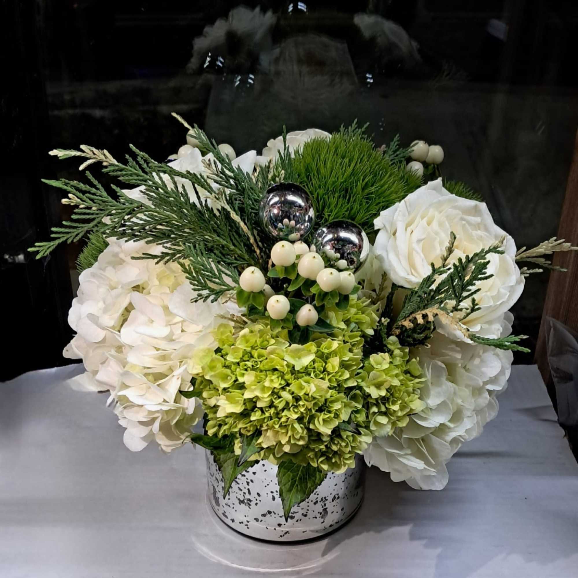 This beautiful arrangement has white roses, white and green hydrangeas, hypericums, small