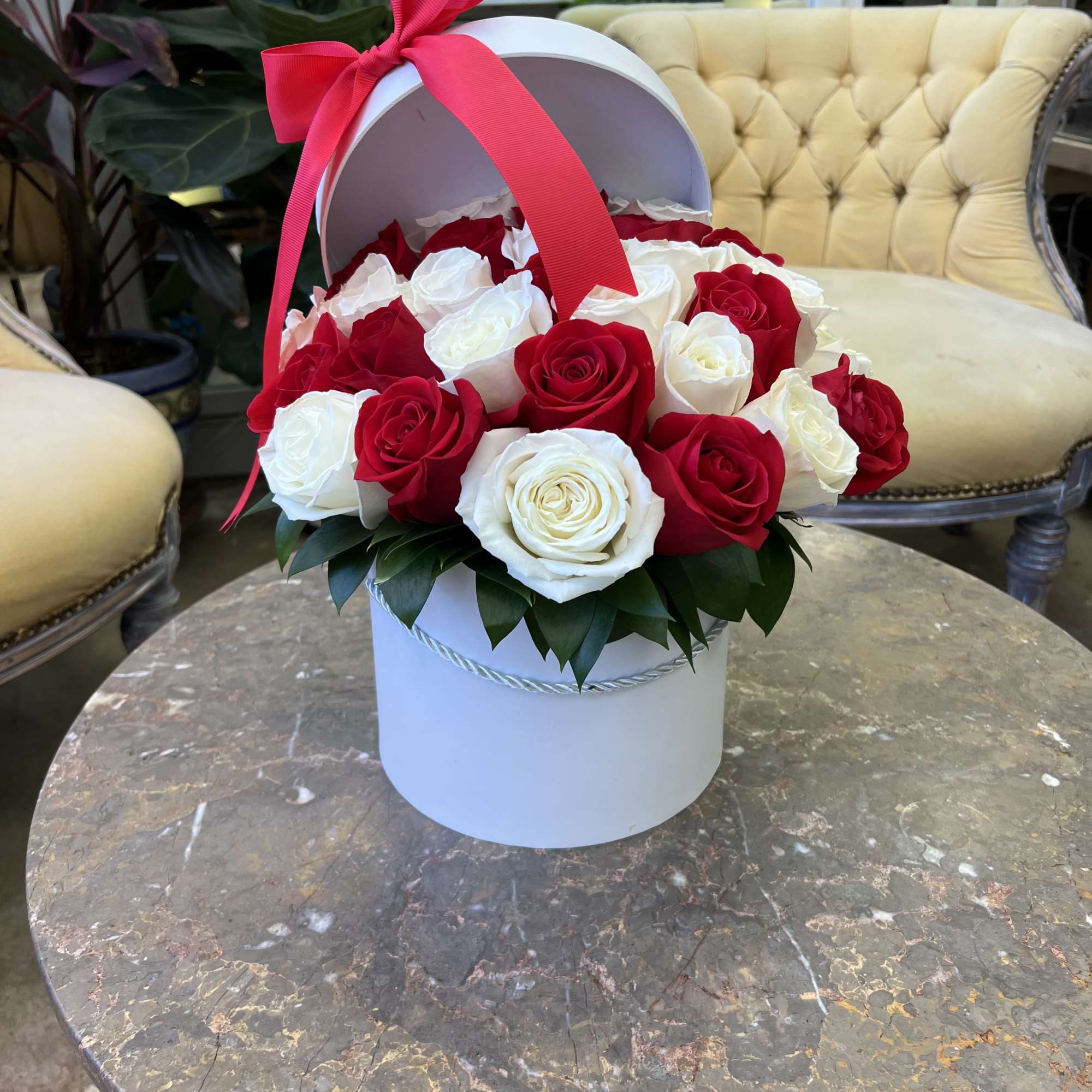 A luxurious round hat box overflowing with fresh, hand-selected roses in timeless