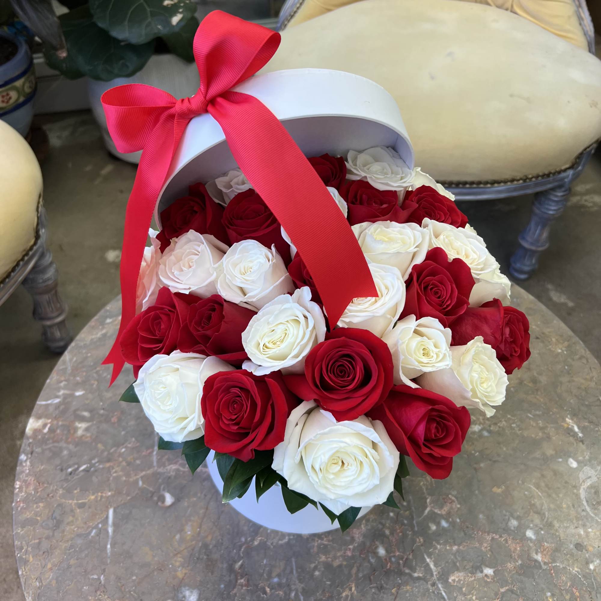 A luxurious round hat box overflowing with fresh, hand-selected roses in timeless