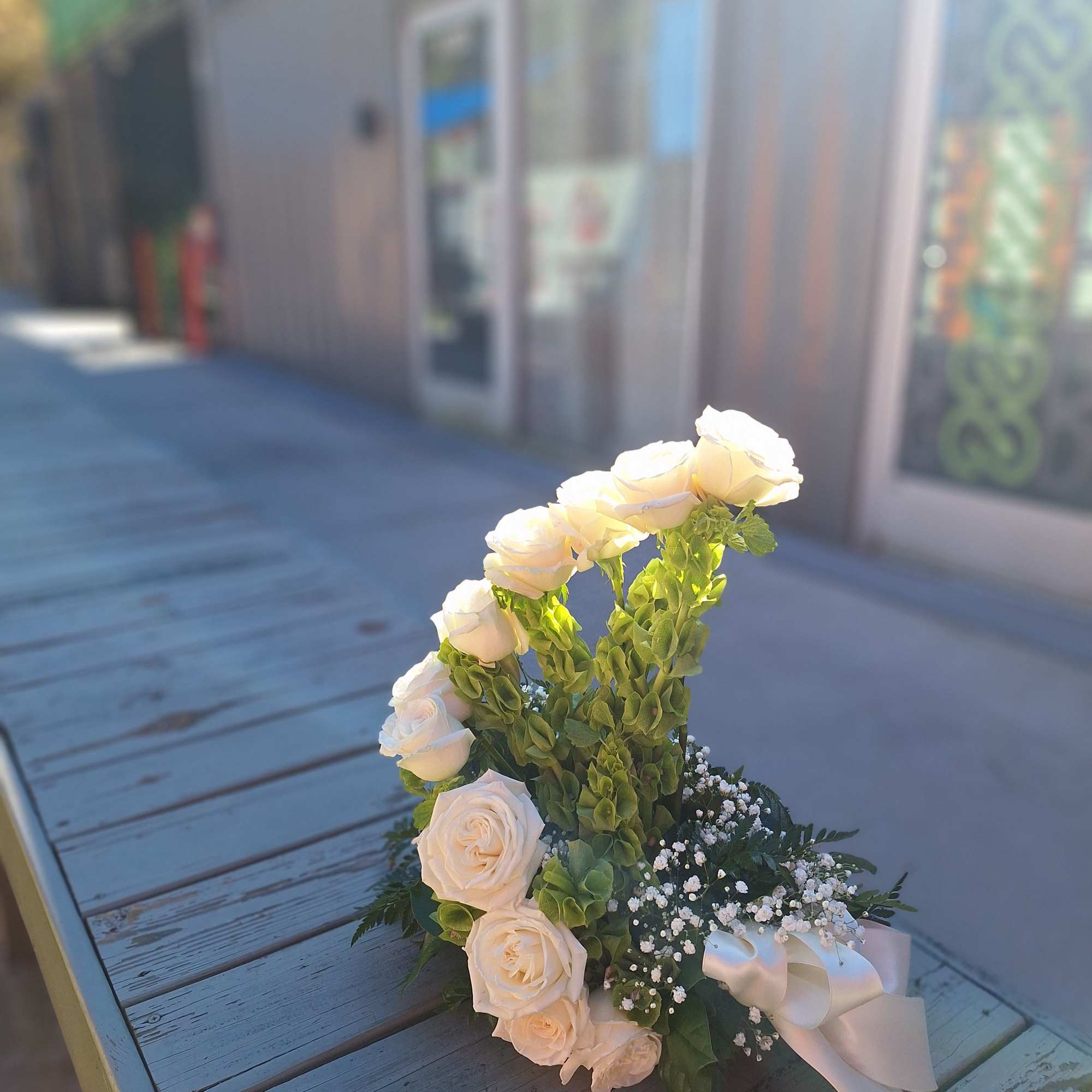 White roses arranged in a cascading spiral with greenery in a modern