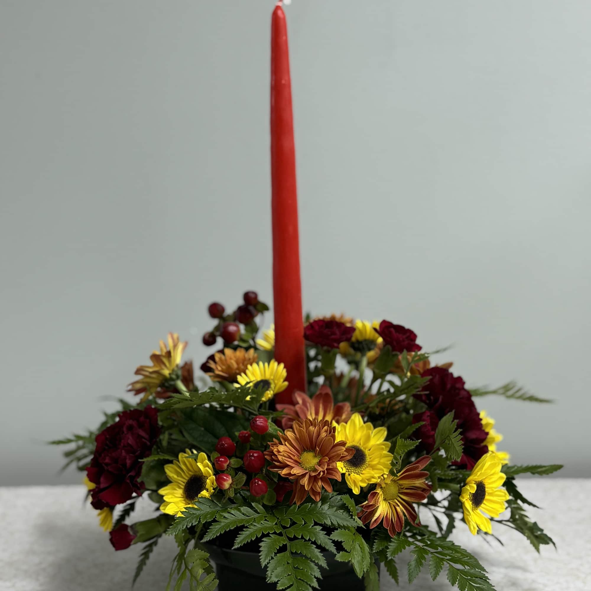 This autumn piece features one candle and a variety of mums, carnations
