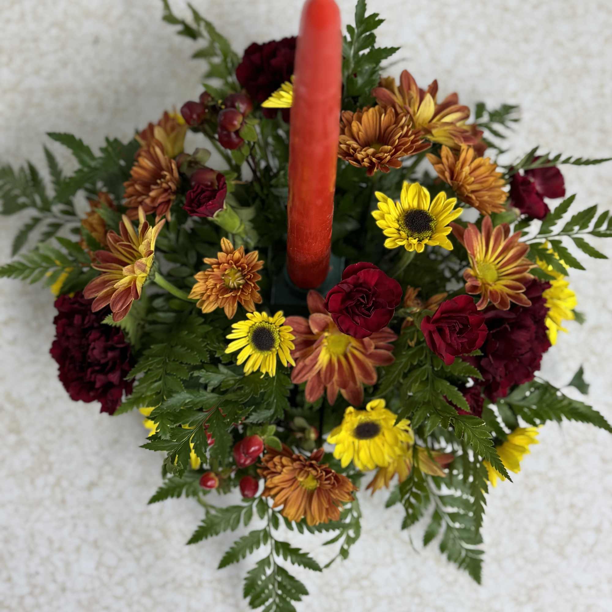 This autumn piece features one candle and a variety of mums, carnations
