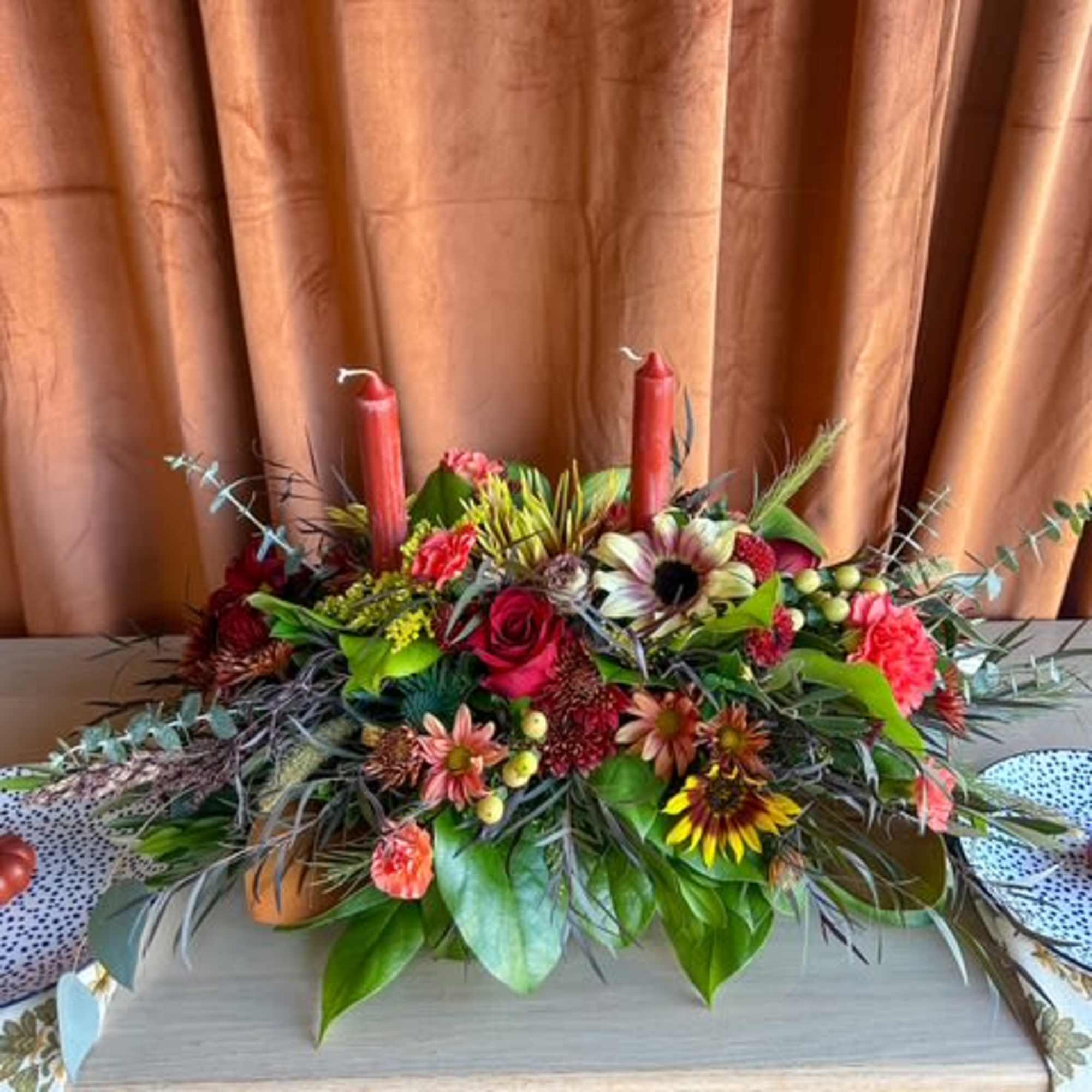 Designed for the Thanksgiving table, this centerpiece blends fresh greenery, fall blooms