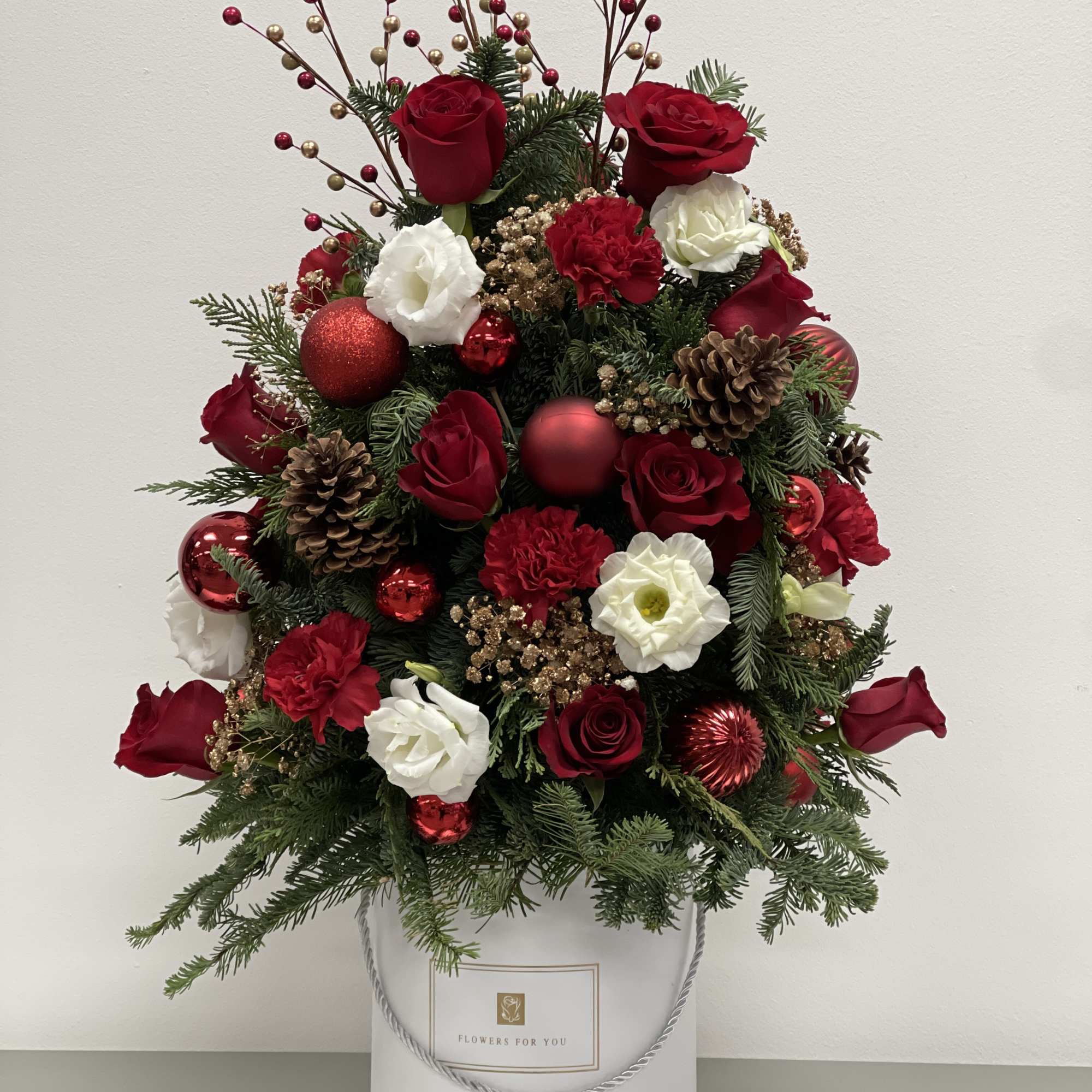 This joyful Christmas tree bouquet includes red roses, red carnations , white