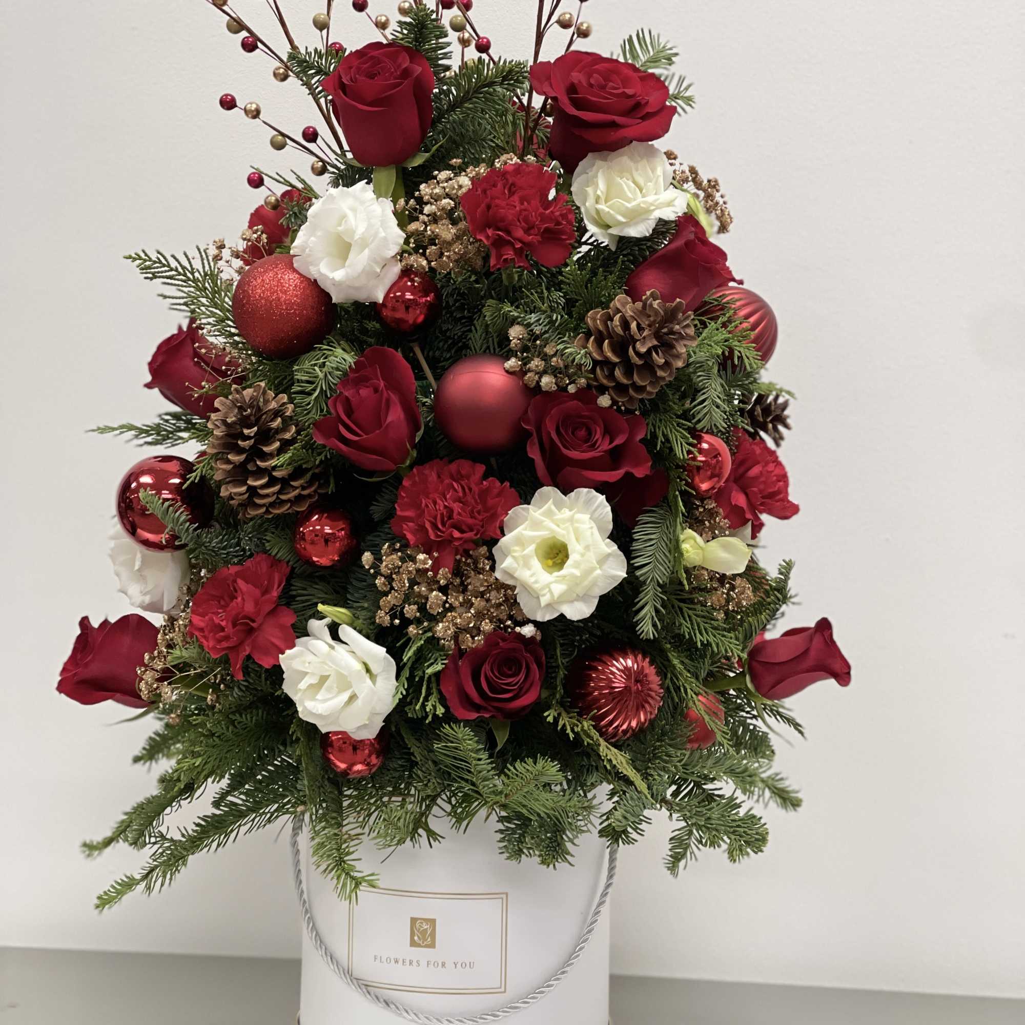 This joyful Christmas tree bouquet includes red roses, red carnations , white