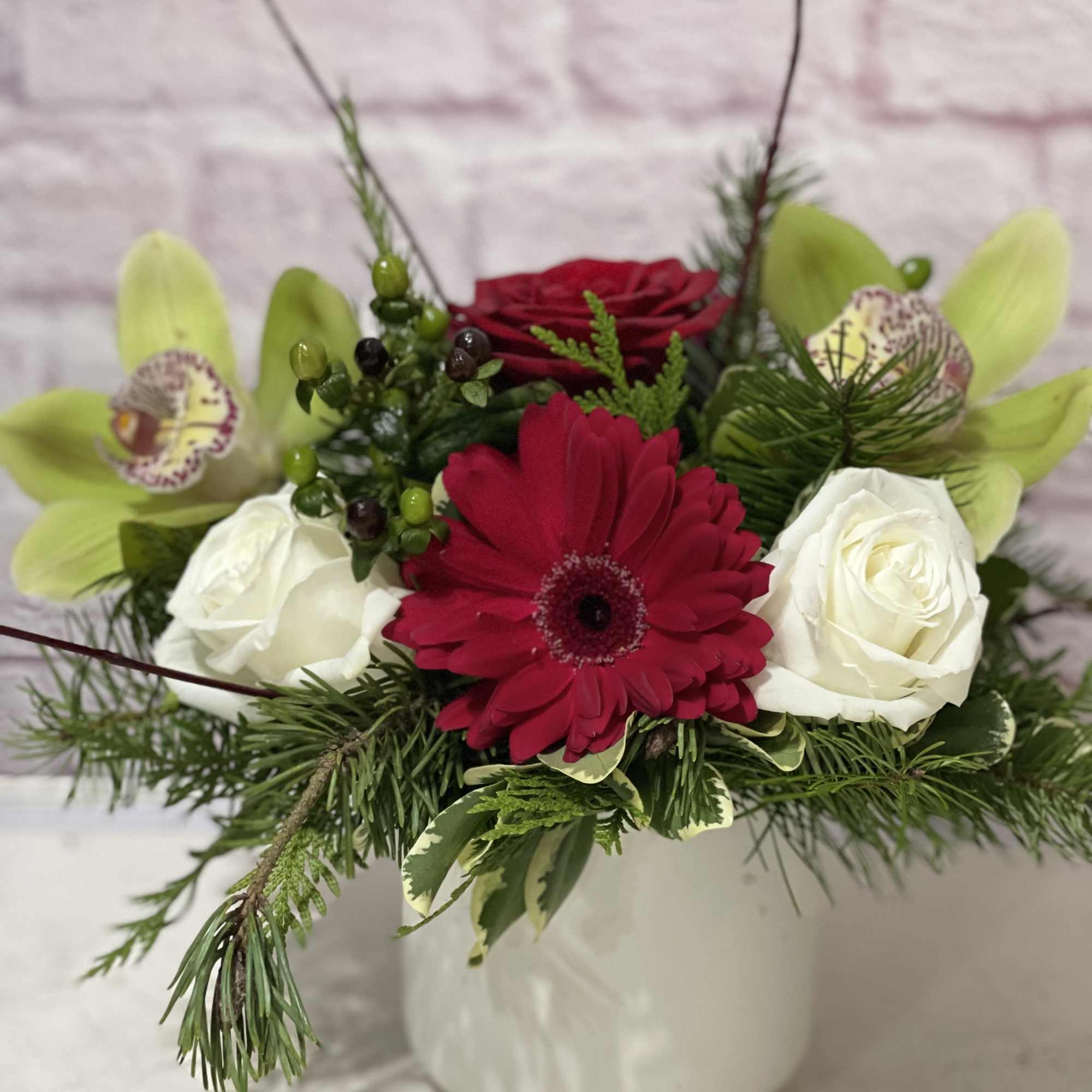 Red, white and green blooms in a white ceramic container. 