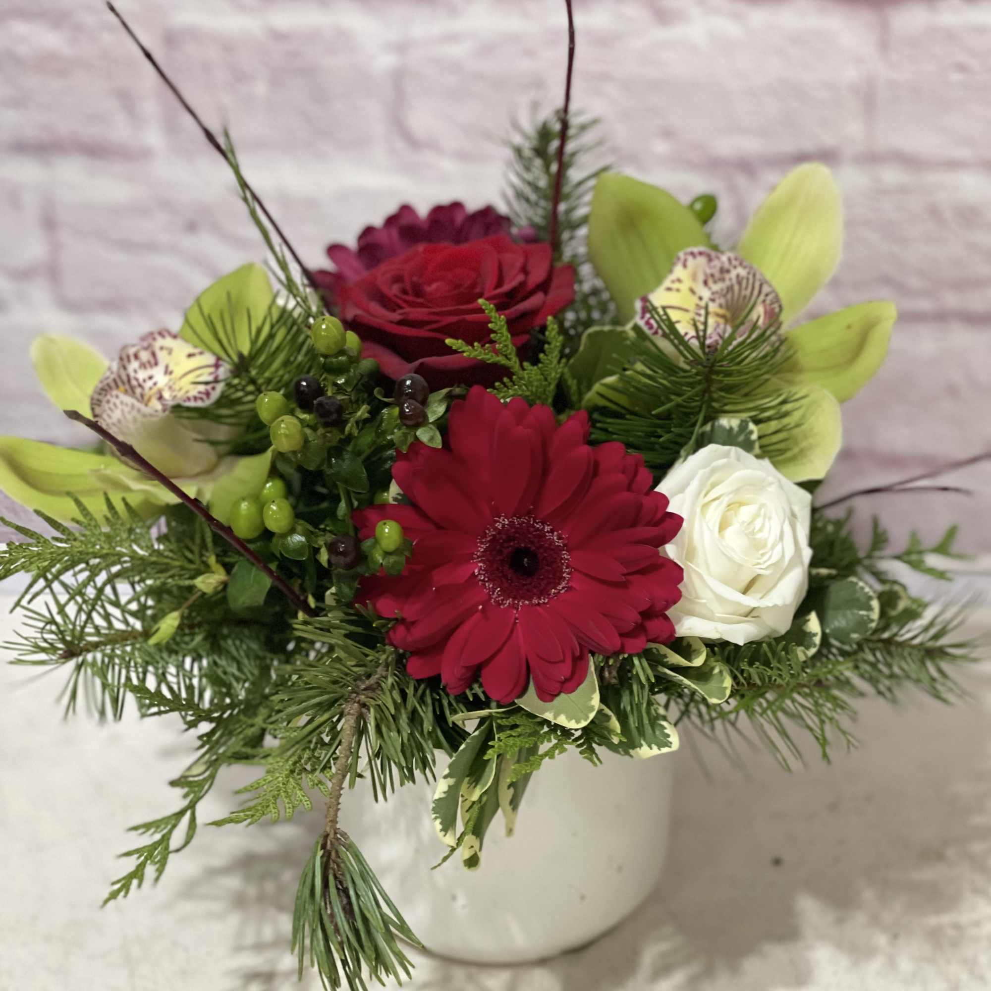 Red, white and green blooms in a white ceramic container. 