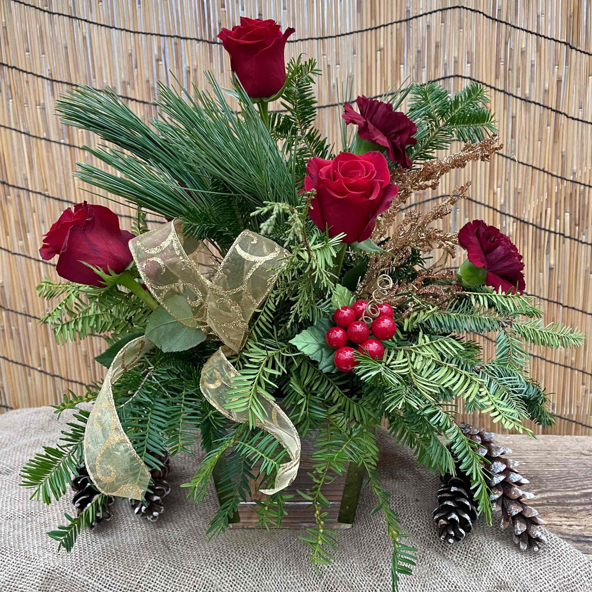 Fresh winter evergreens, with pops of holiday red roses and carnations. Glistening
