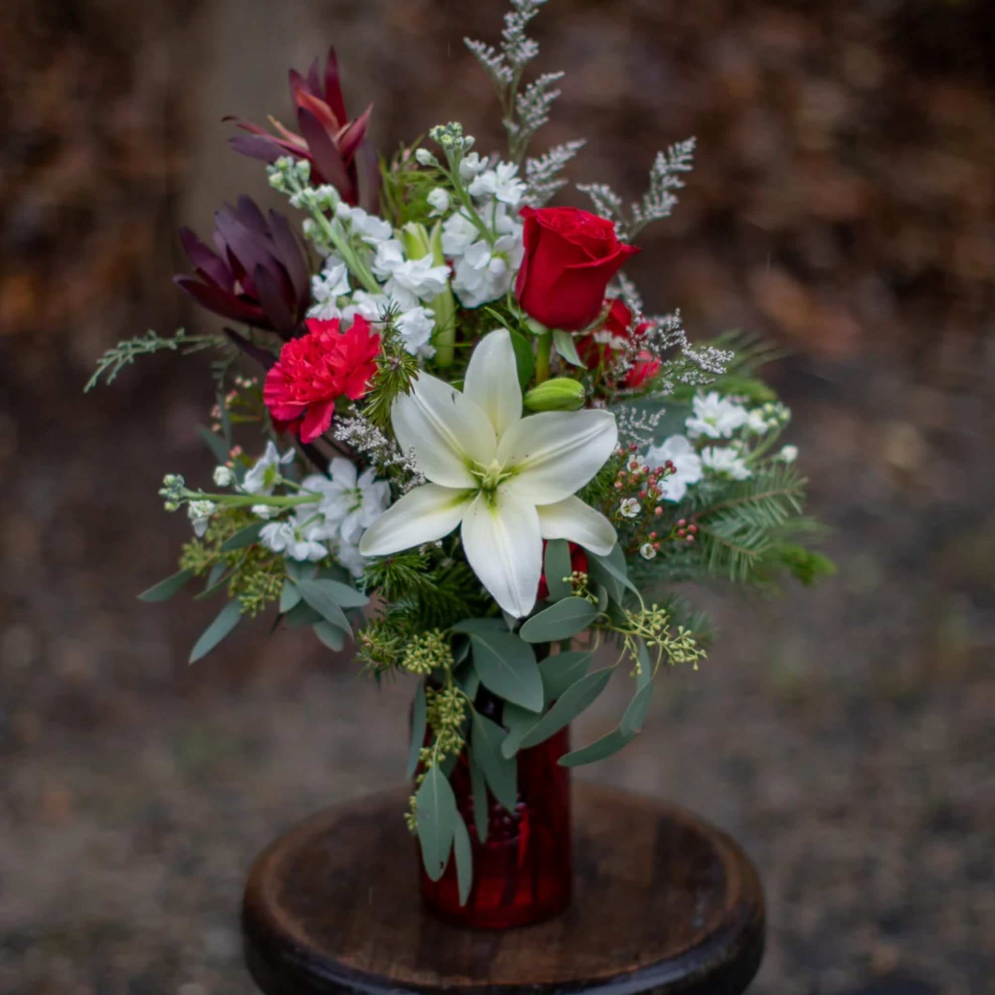 Pretty white lily and red roses with carnations nested on bountiful winter