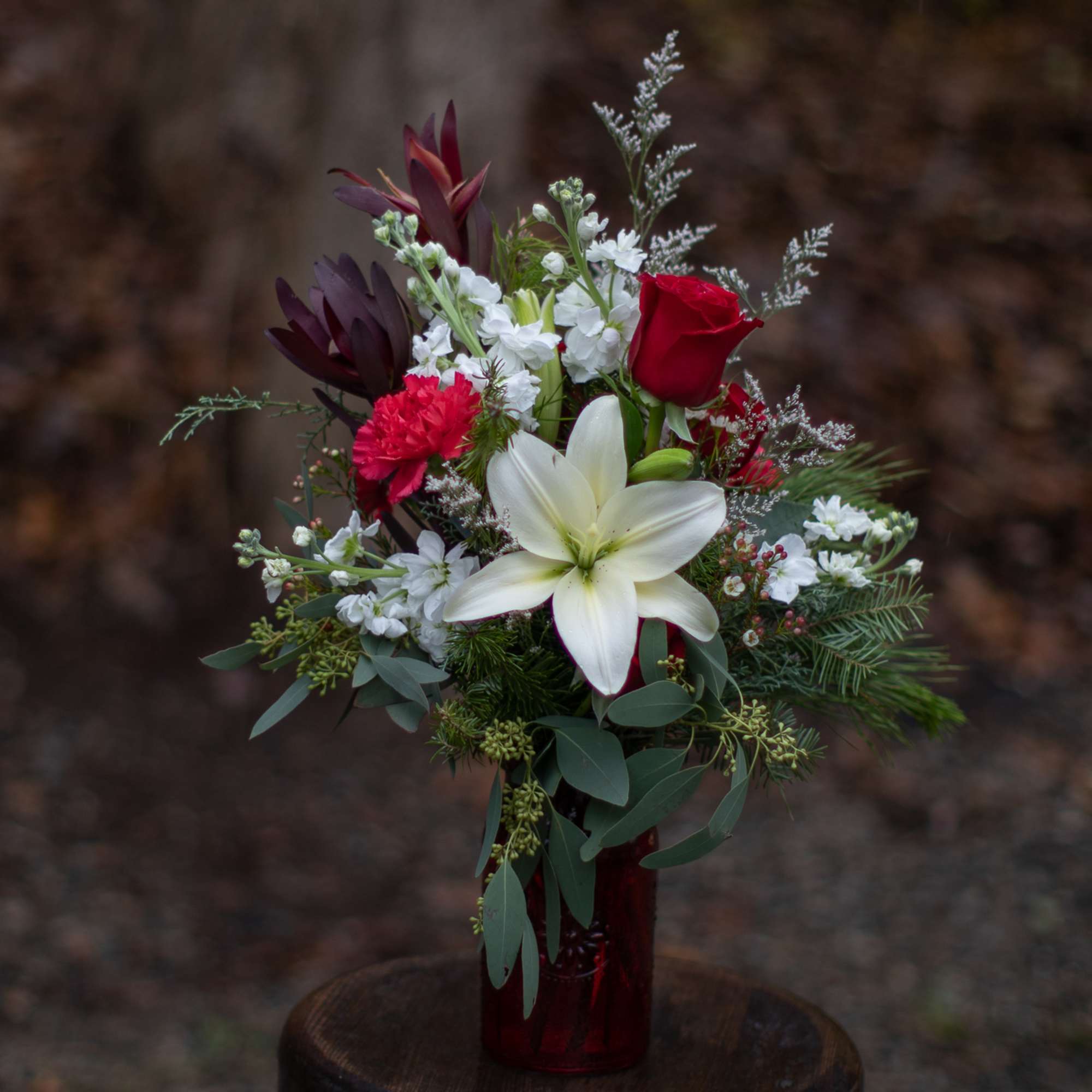 Pretty white lily and red roses with carnations nested on bountiful winter