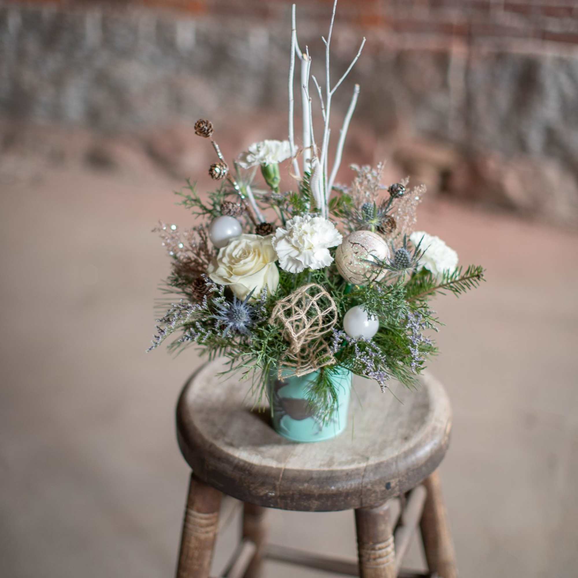 Winter foliage is artfully arranged in a coastal inspired tin container. This