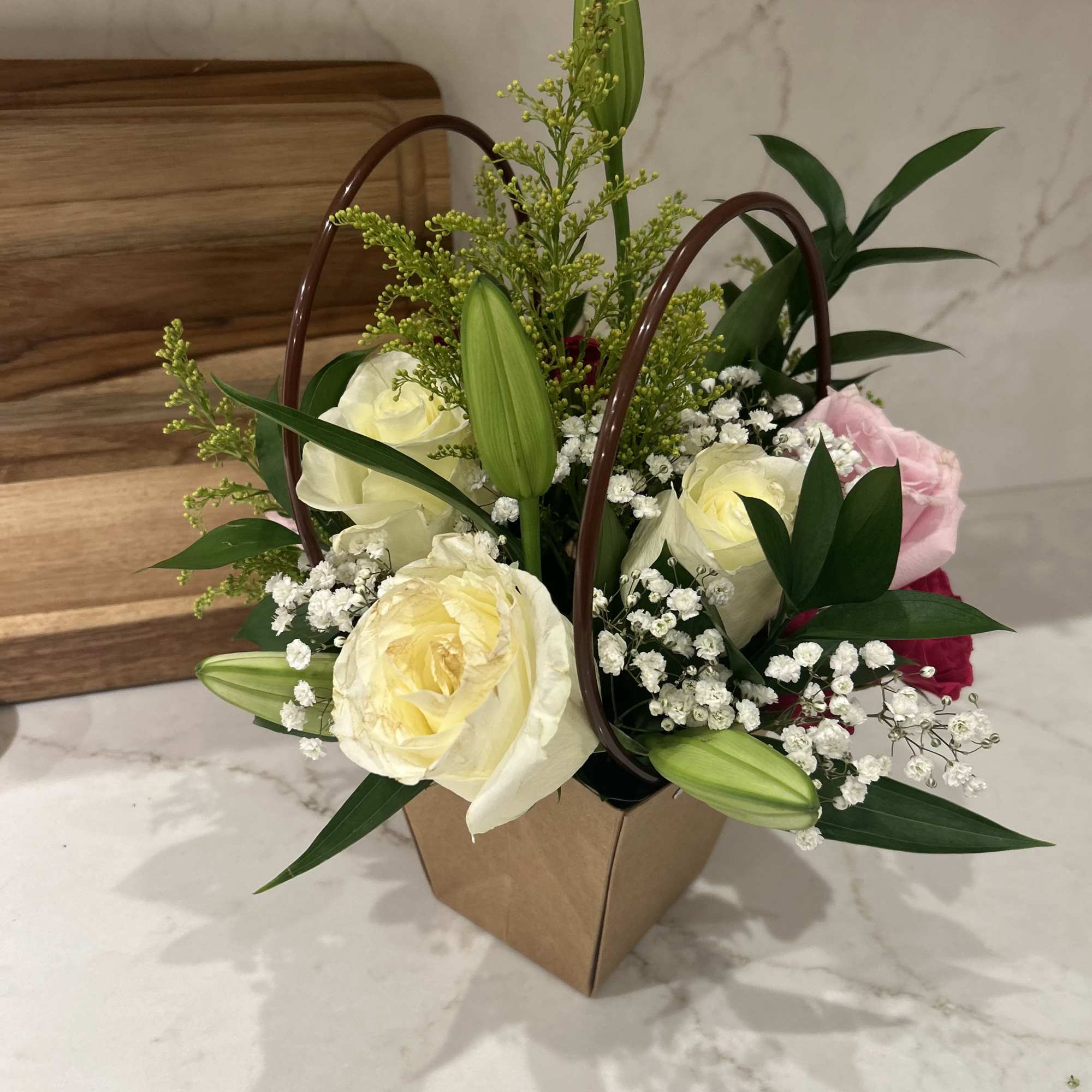 The Brown Bag Special is a small arrangement containing roses and lilies
