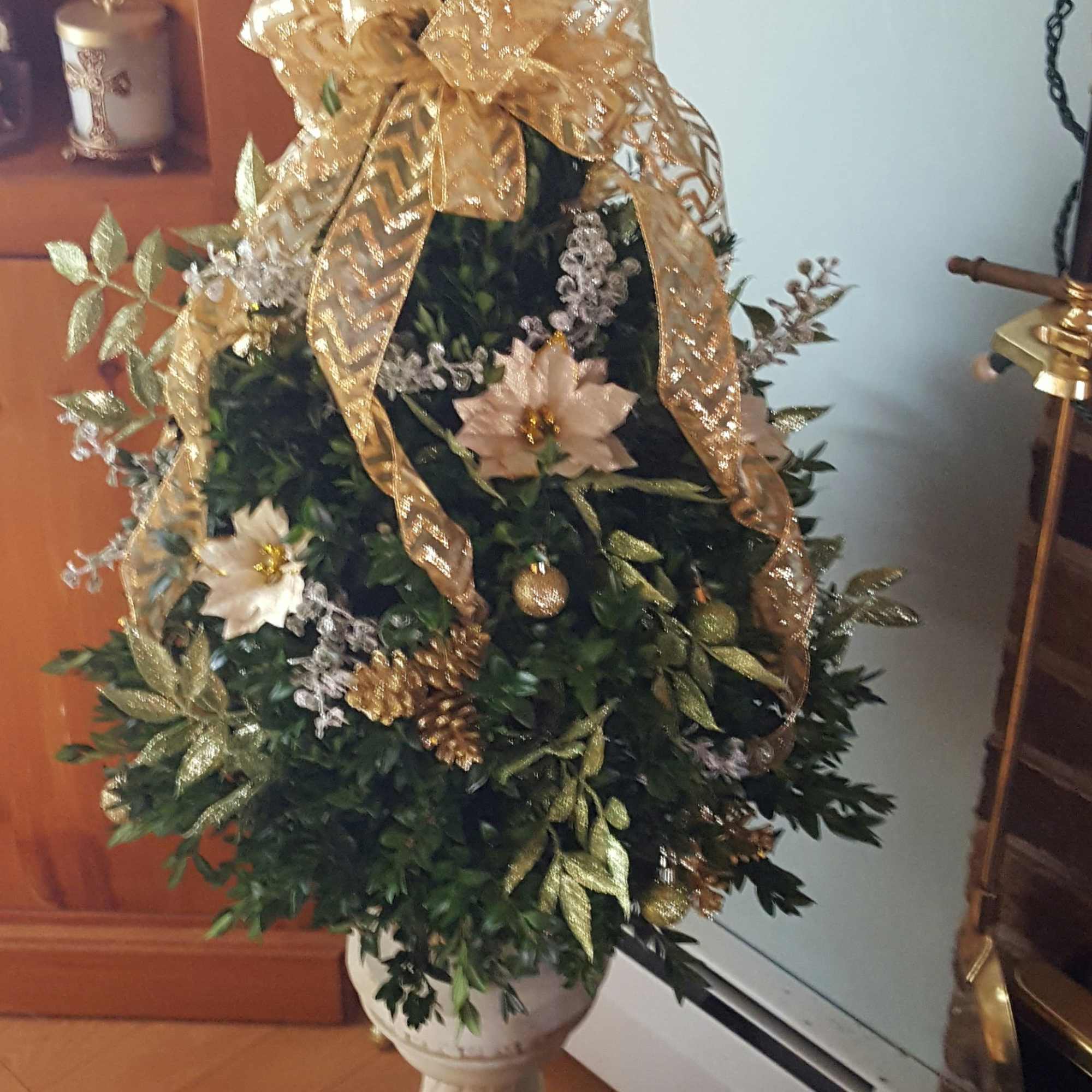 A table top boxwood Christmas tree decorated with flowers, fillers, balls, pinecones