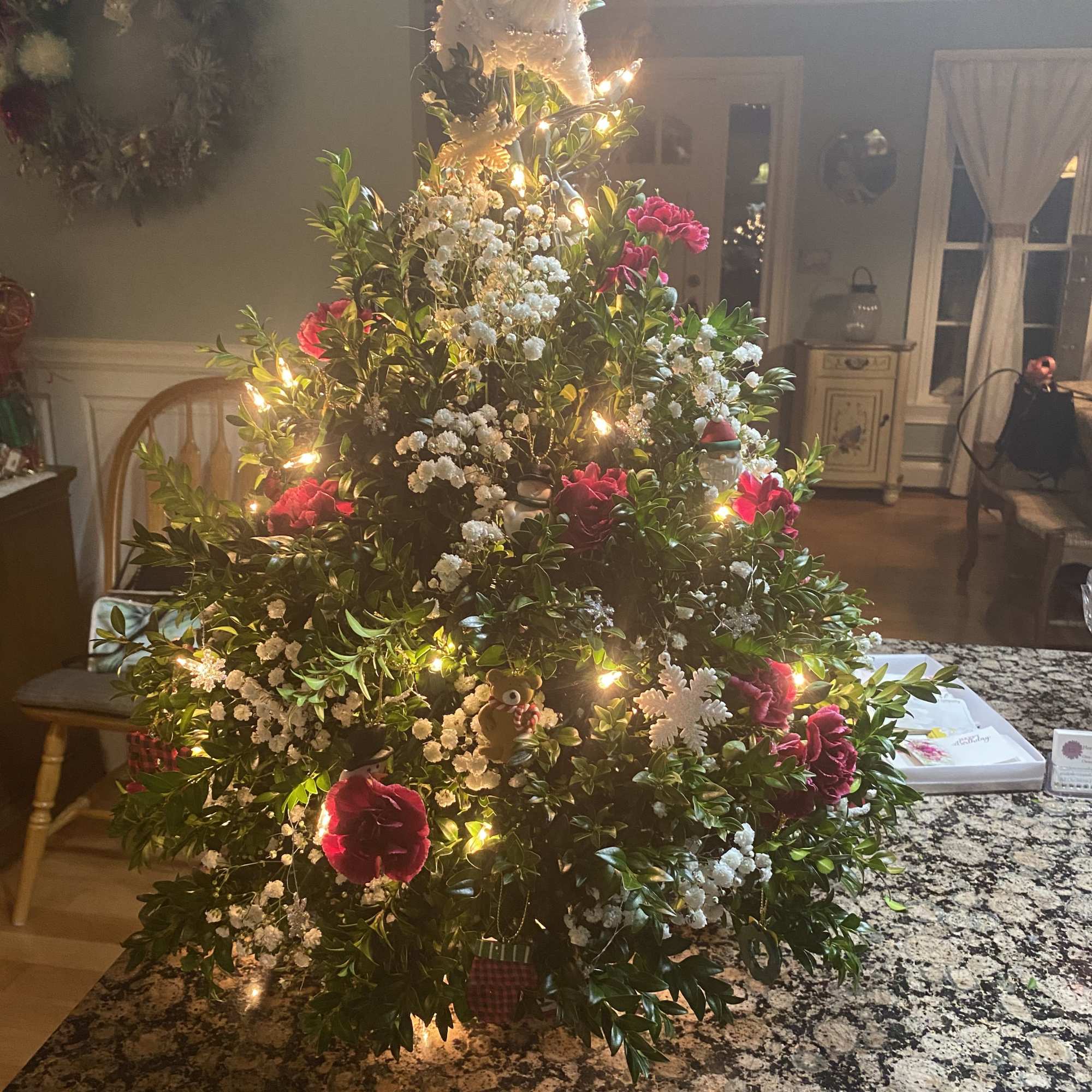 A table top boxwood Christmas tree decorated with flowers, fillers, balls, pinecones