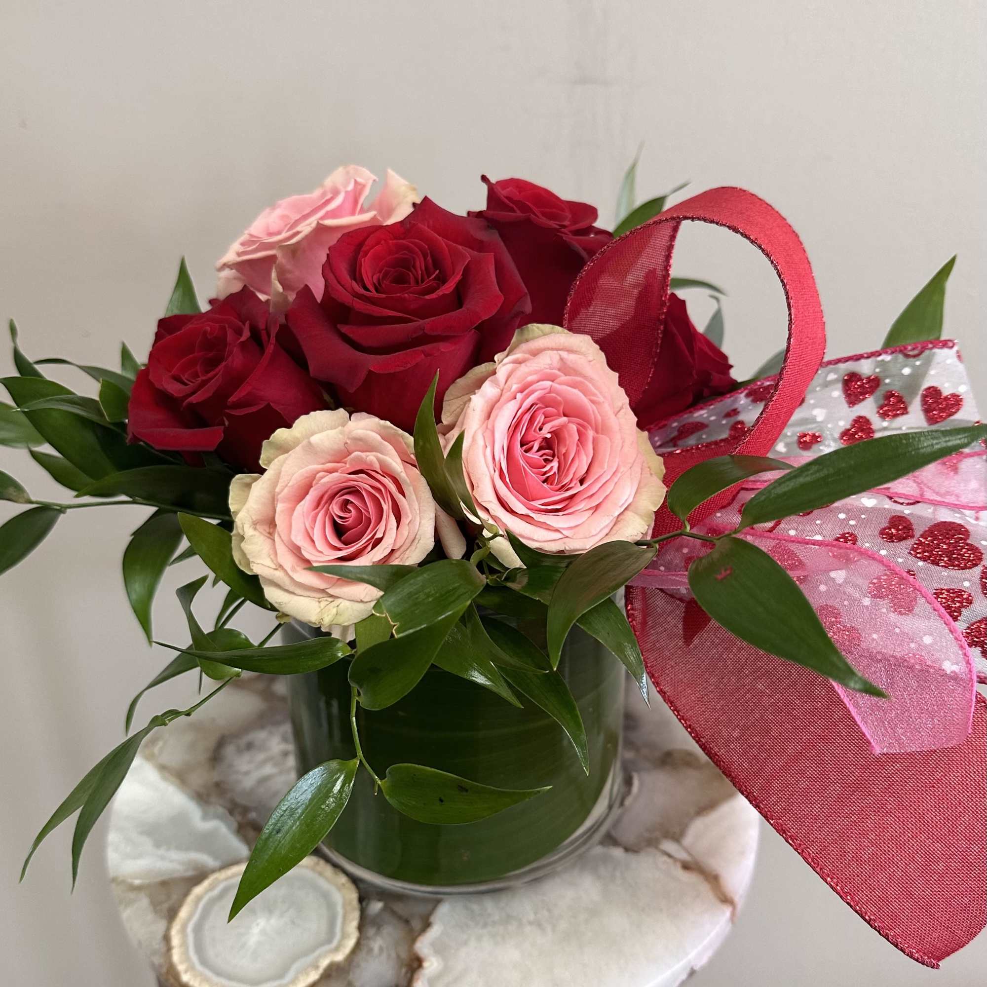 A short and modern styled arrangement of red and pink roses. The
