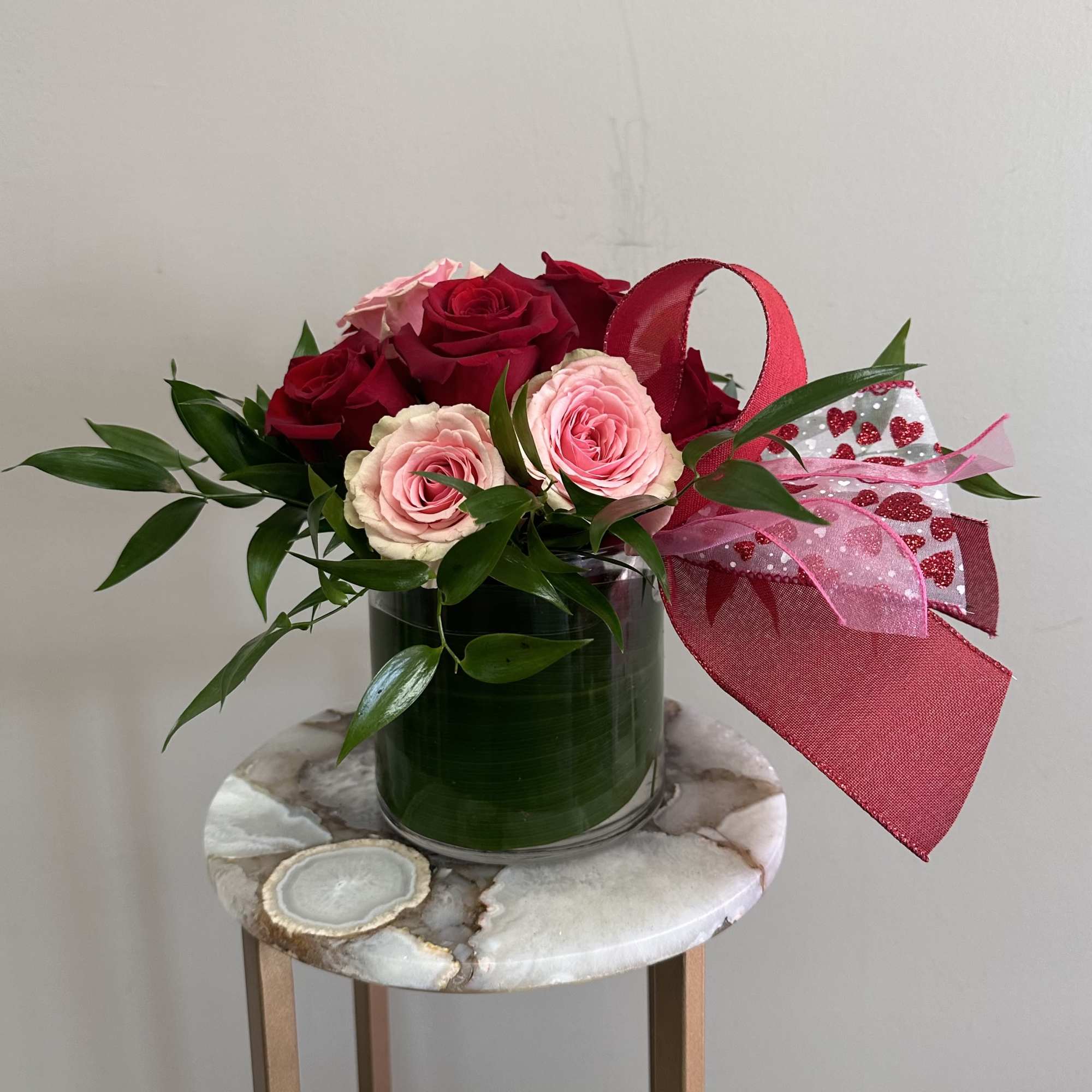 A short and modern styled arrangement of red and pink roses. The