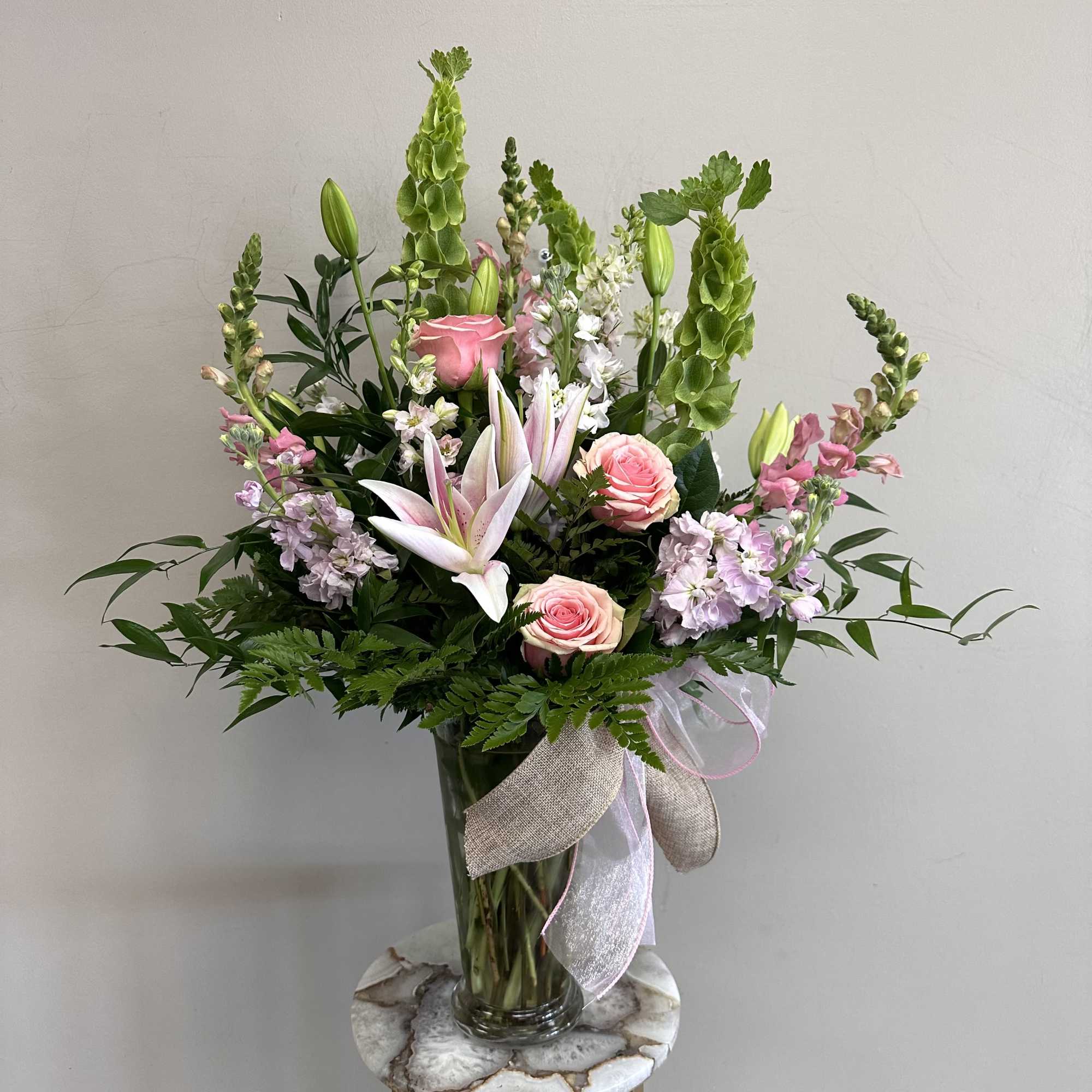 Soft pink larkspur, snap dragons, roses, lilies, stock and lisianthus meet in