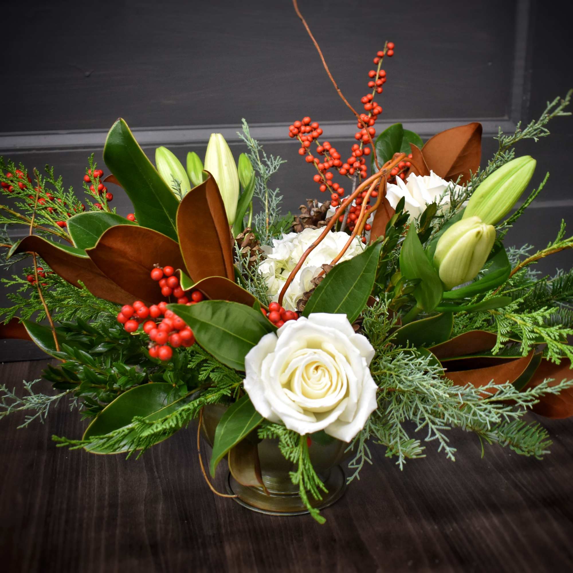 A harmonious mix of winter greenery, magnolia, red berries, fluffy hydrangea, pinecones