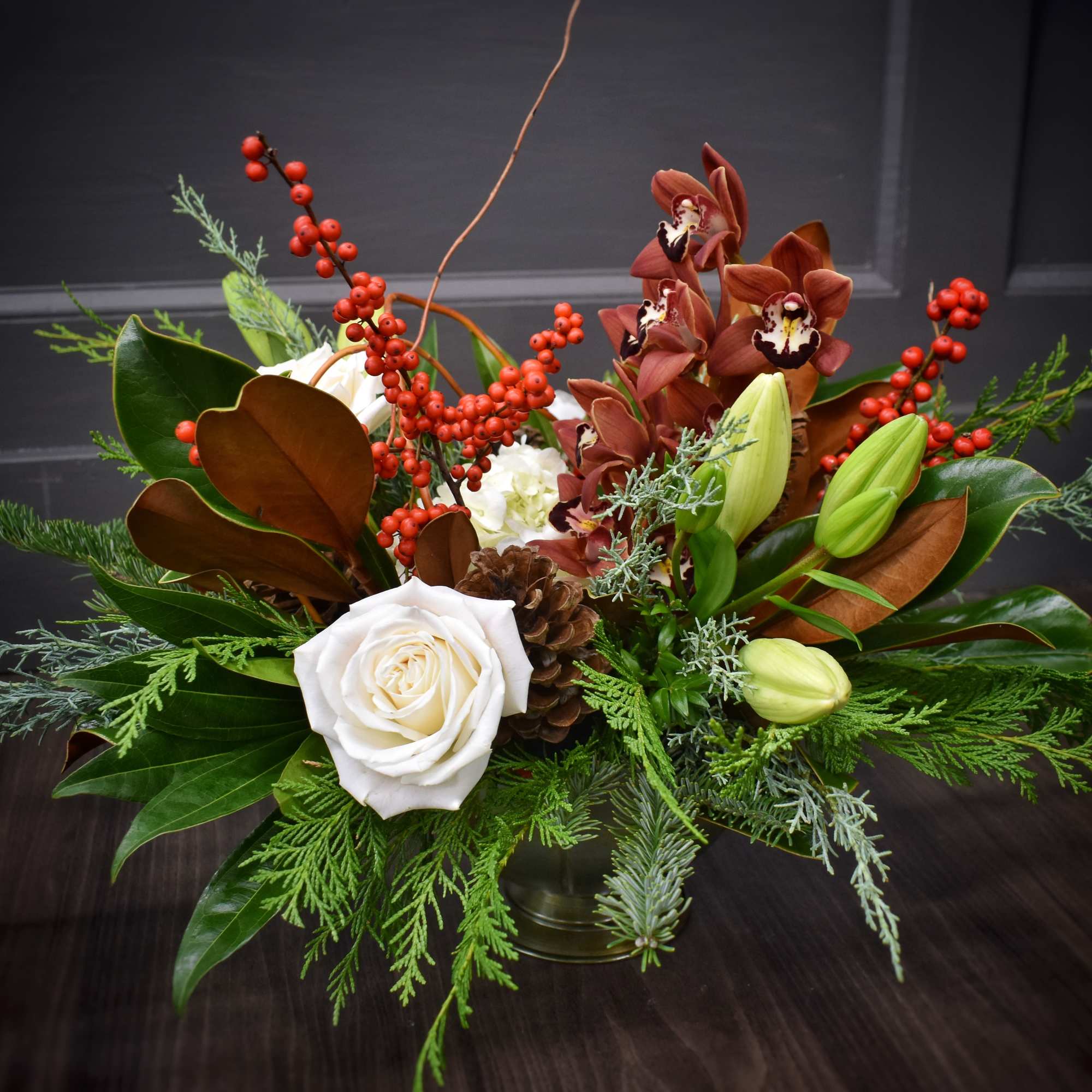 A harmonious mix of winter greenery, magnolia, red berries, fluffy hydrangea, pinecones