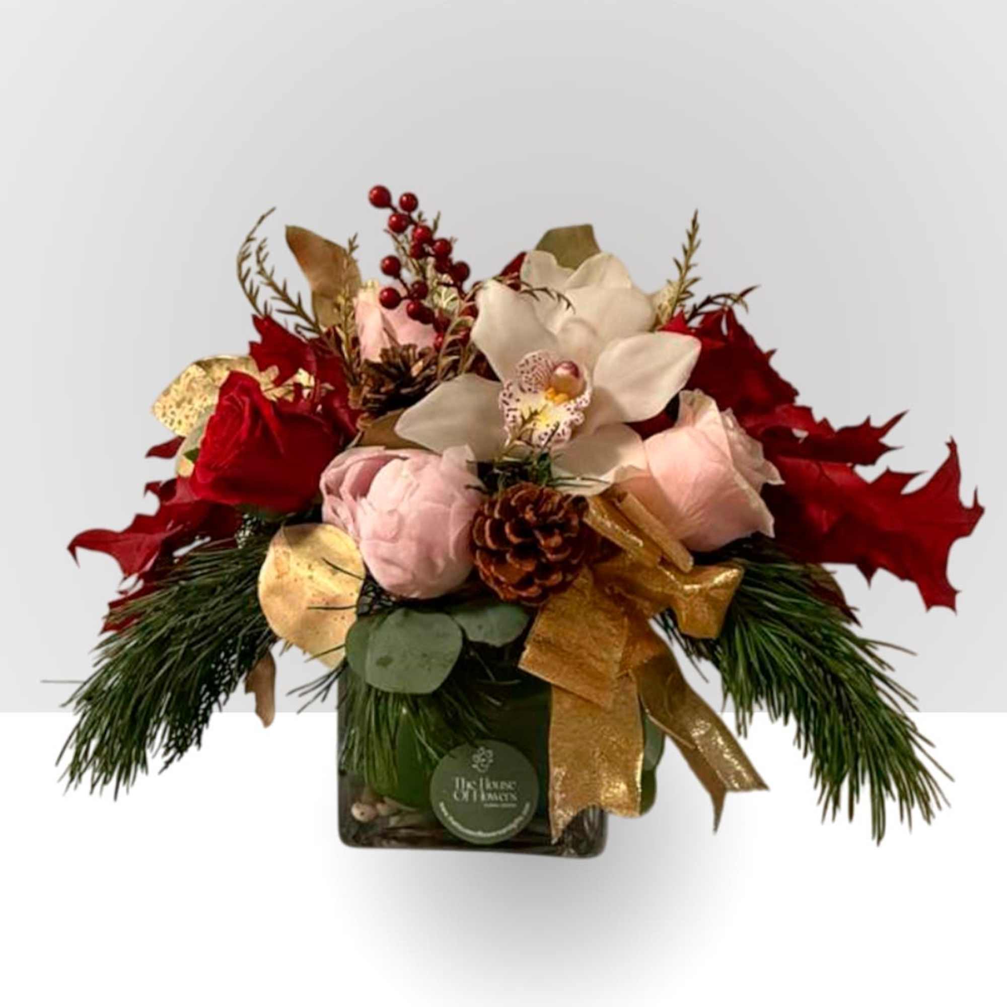 An elegant holiday arrangement featuring classic red roses, soft blush blooms, winter