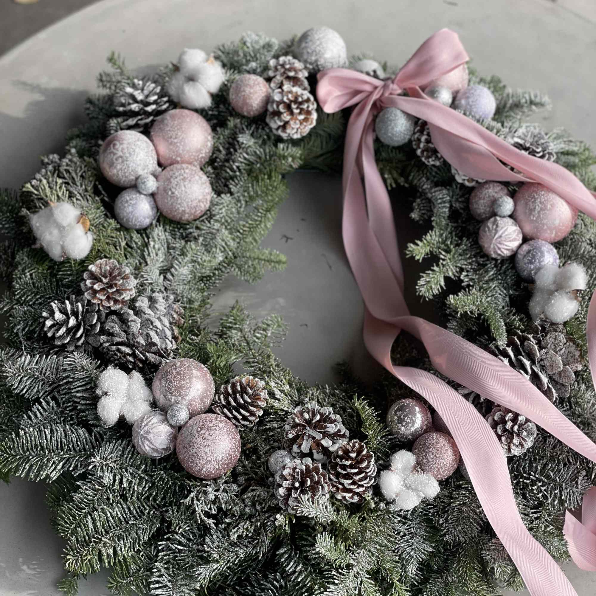 This soft and elegant holiday wreath features fresh snowy evergreens adorned with