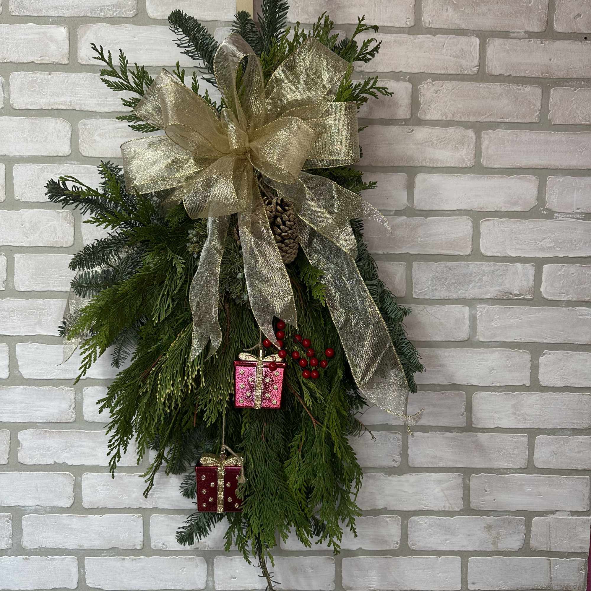Festive mix of winter greens, pinecones, and festive ribbon combined in a