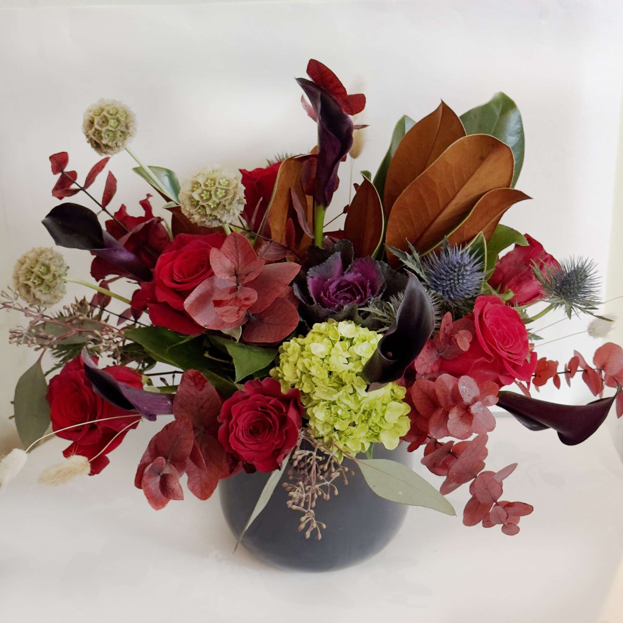 This arrangement is presented in a dark blue cylinder vase. It features