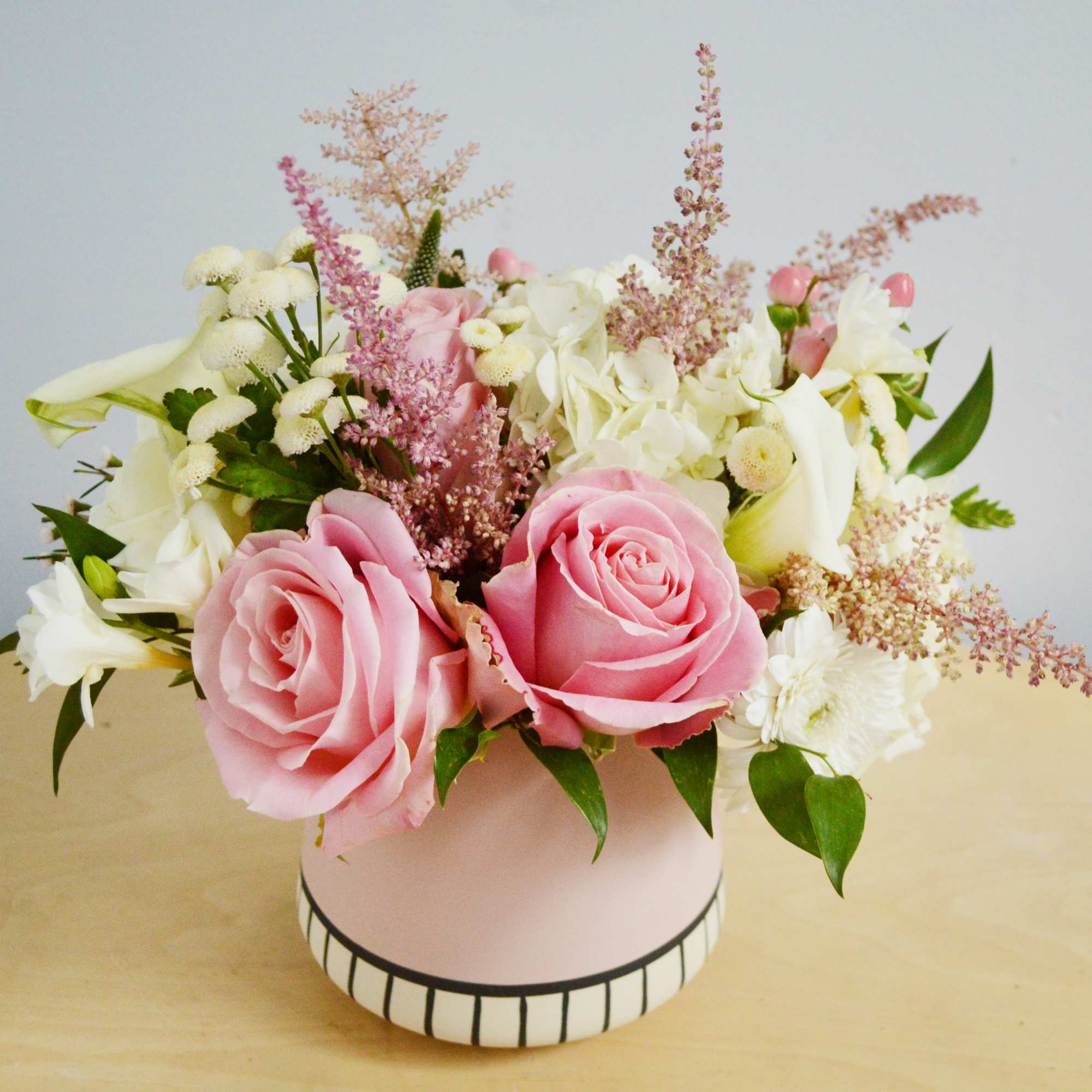 This arrangement features pastel color Hersoma rose, white calla lily, white hydrangea