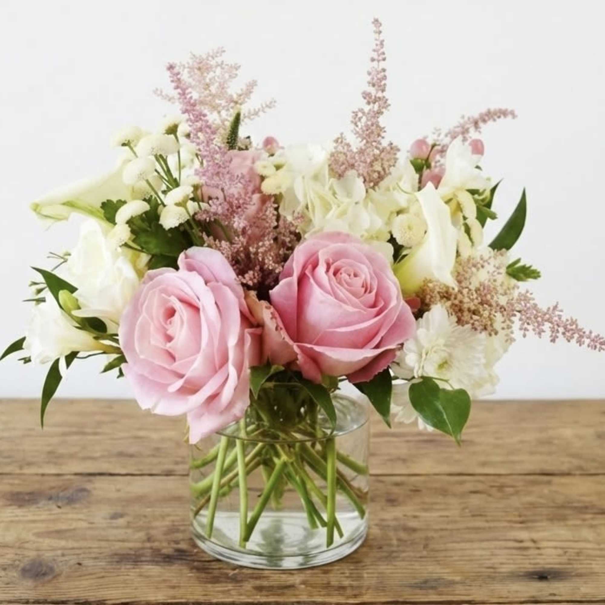 This arrangement features pastel color Hersoma rose, white calla lily, white hydrangea