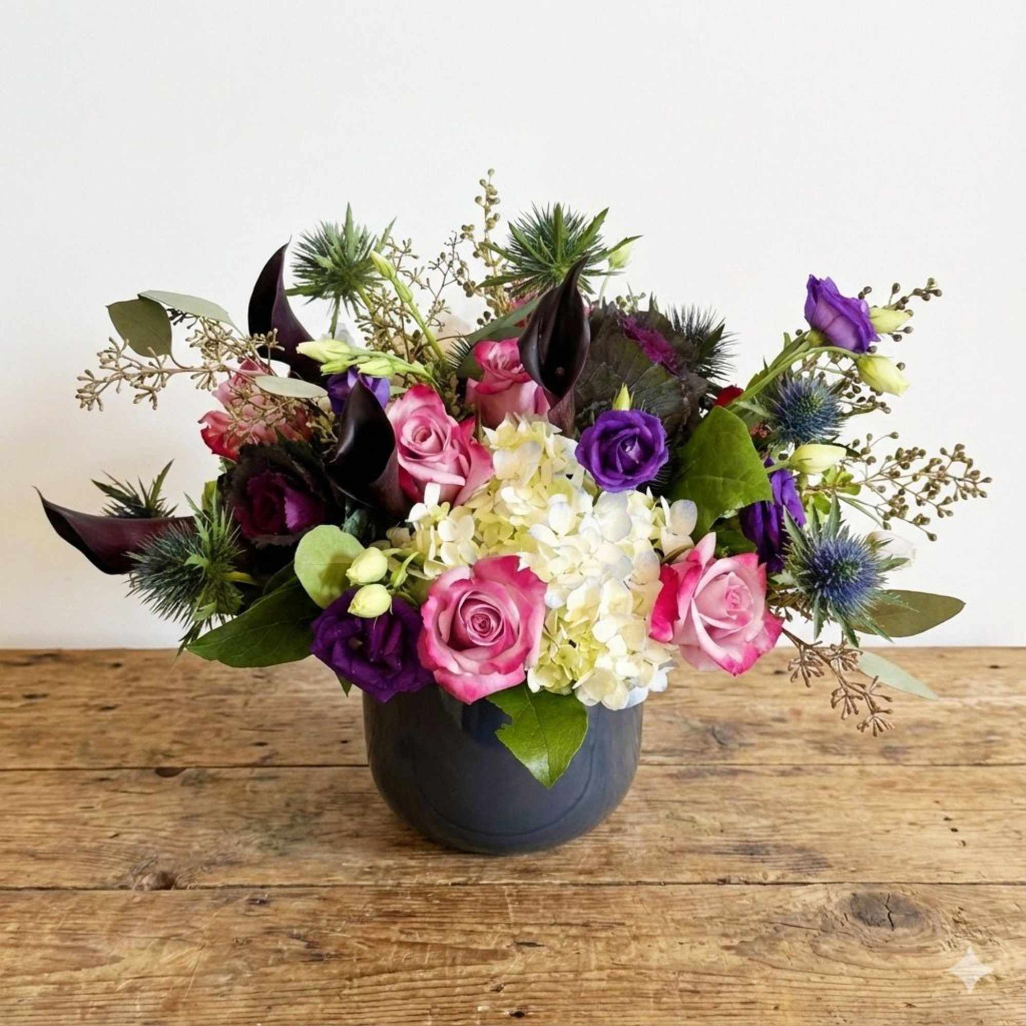 This arrangement is presented in a dark blue glass vase. It feature