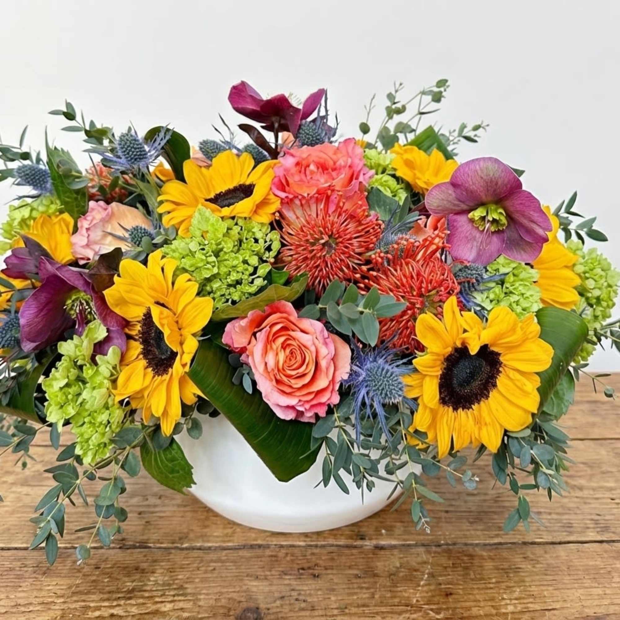 This arrangement includes sunflowers, green hydrangeas, pincushions, free spirit roses, burgundy hellebore