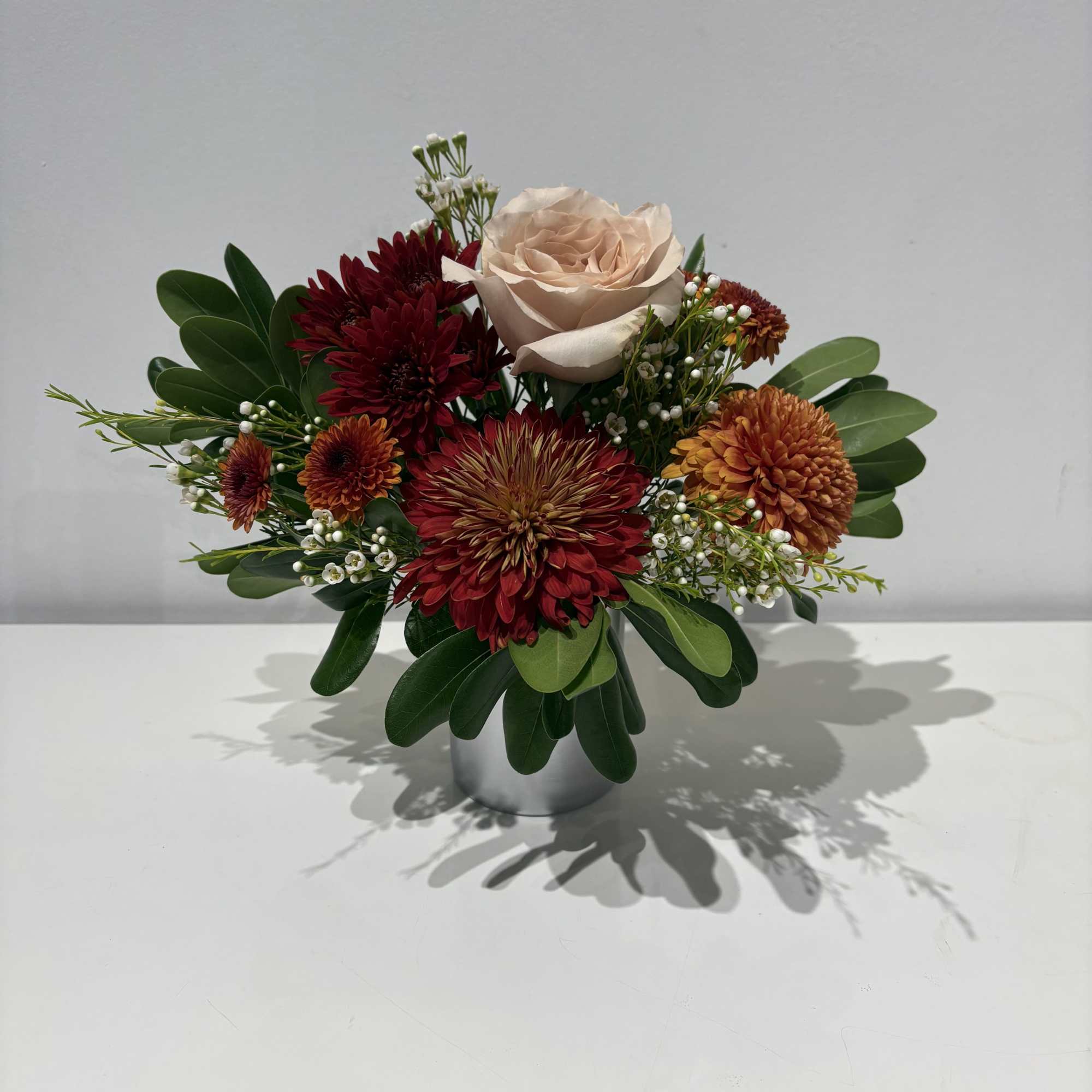 A glass cup holding an array of fresh cut Florals in seasonal