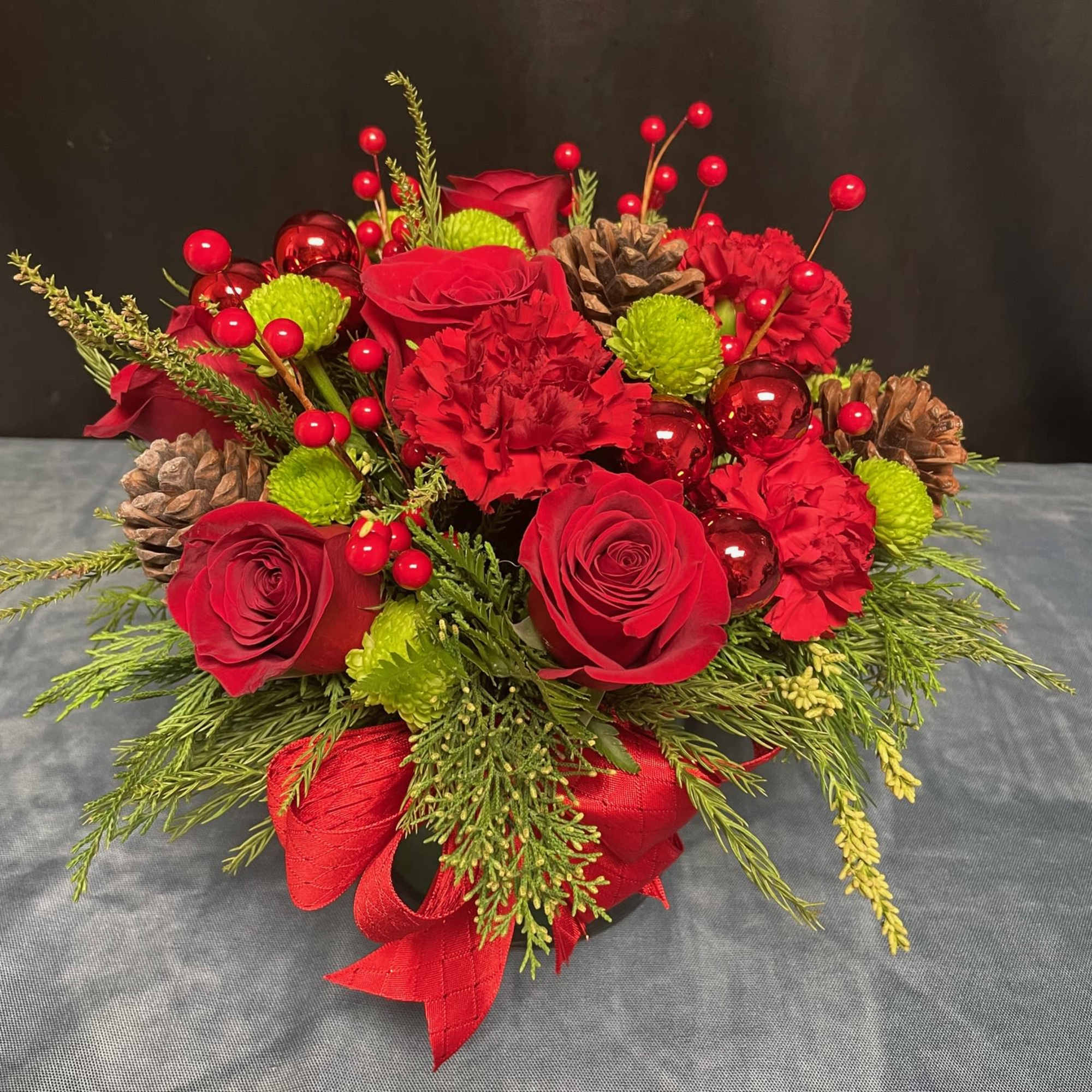 Red Roses, Red carnations, Green Buttons, Pinecones, Mm balls, and Faux Berries.