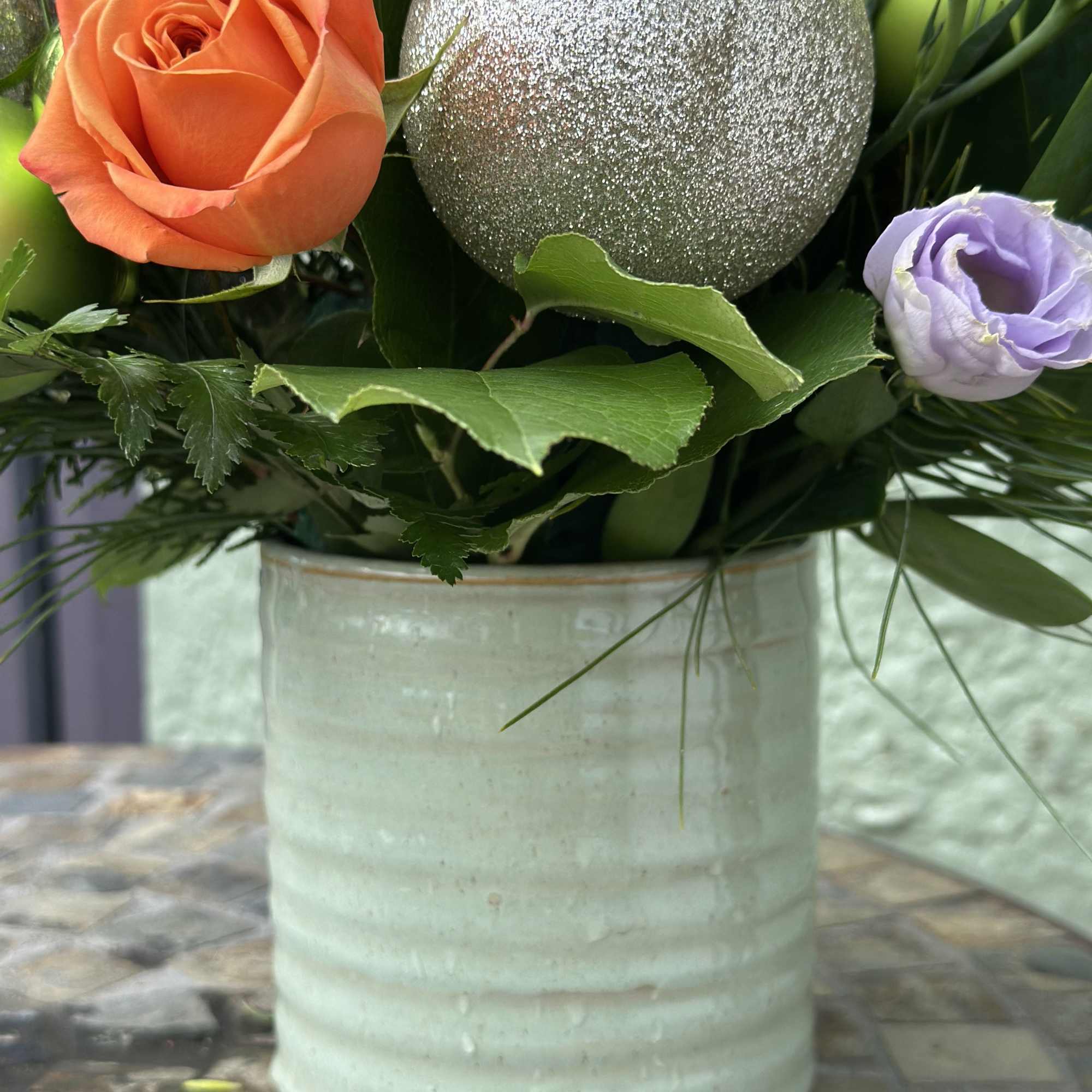 A playful fusion of soft elegance and holiday cheer, this arrangement brings