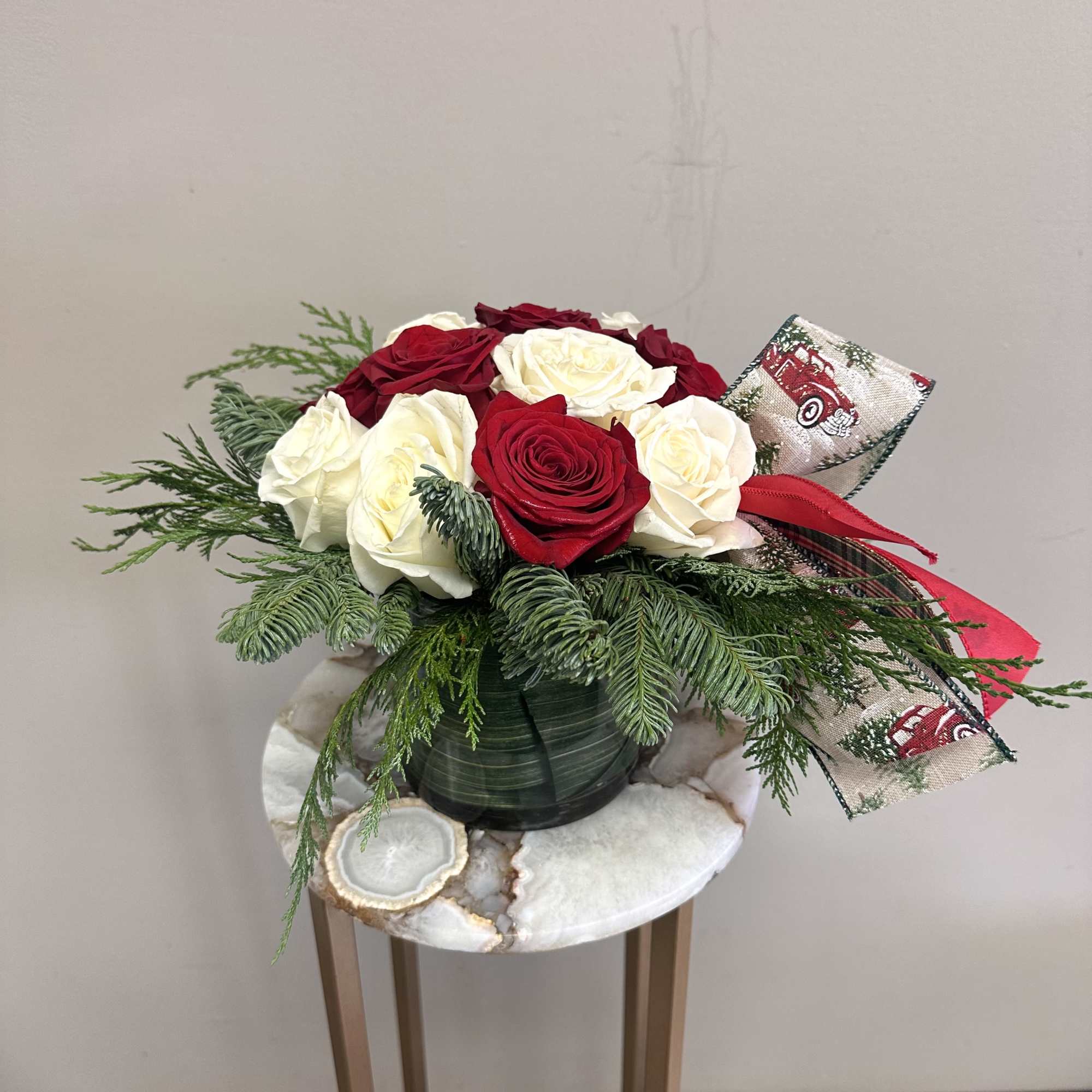 A short and modern styled red and white rose arrangement with holiday