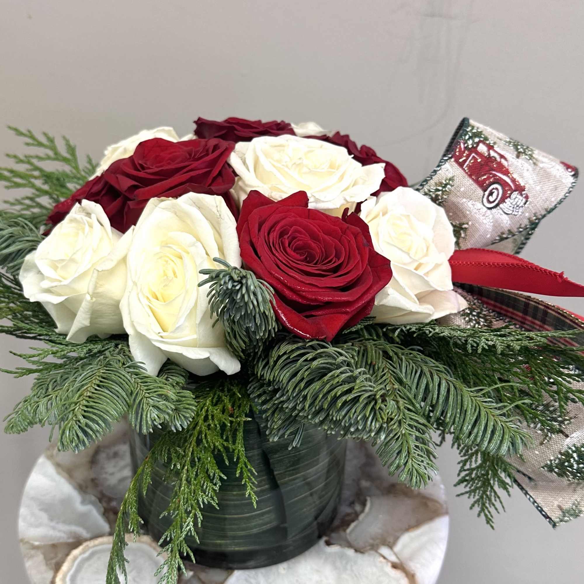 A short and modern styled red and white rose arrangement with holiday