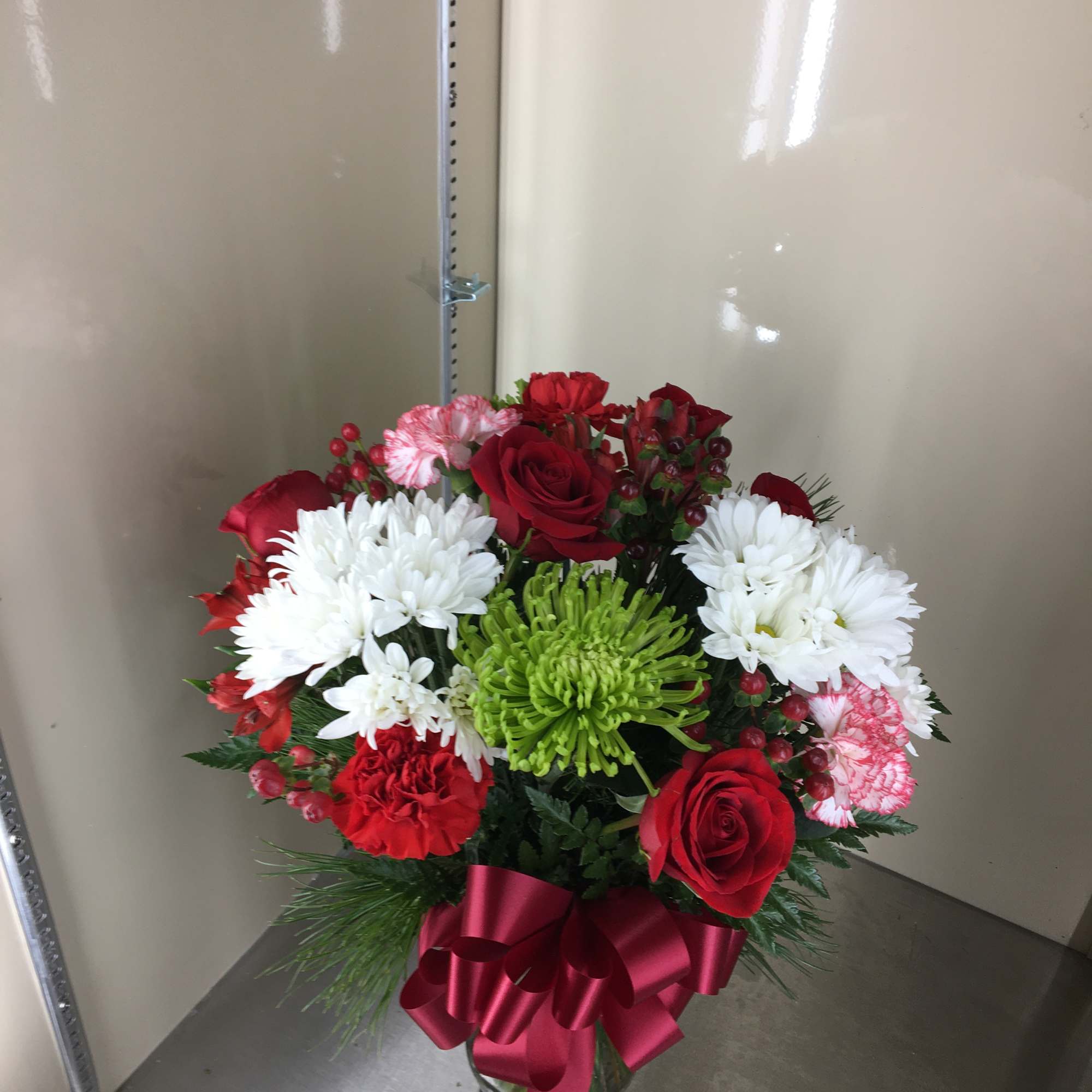 Cut arrangement with red roses, red carnations, white daisies, red berries, green