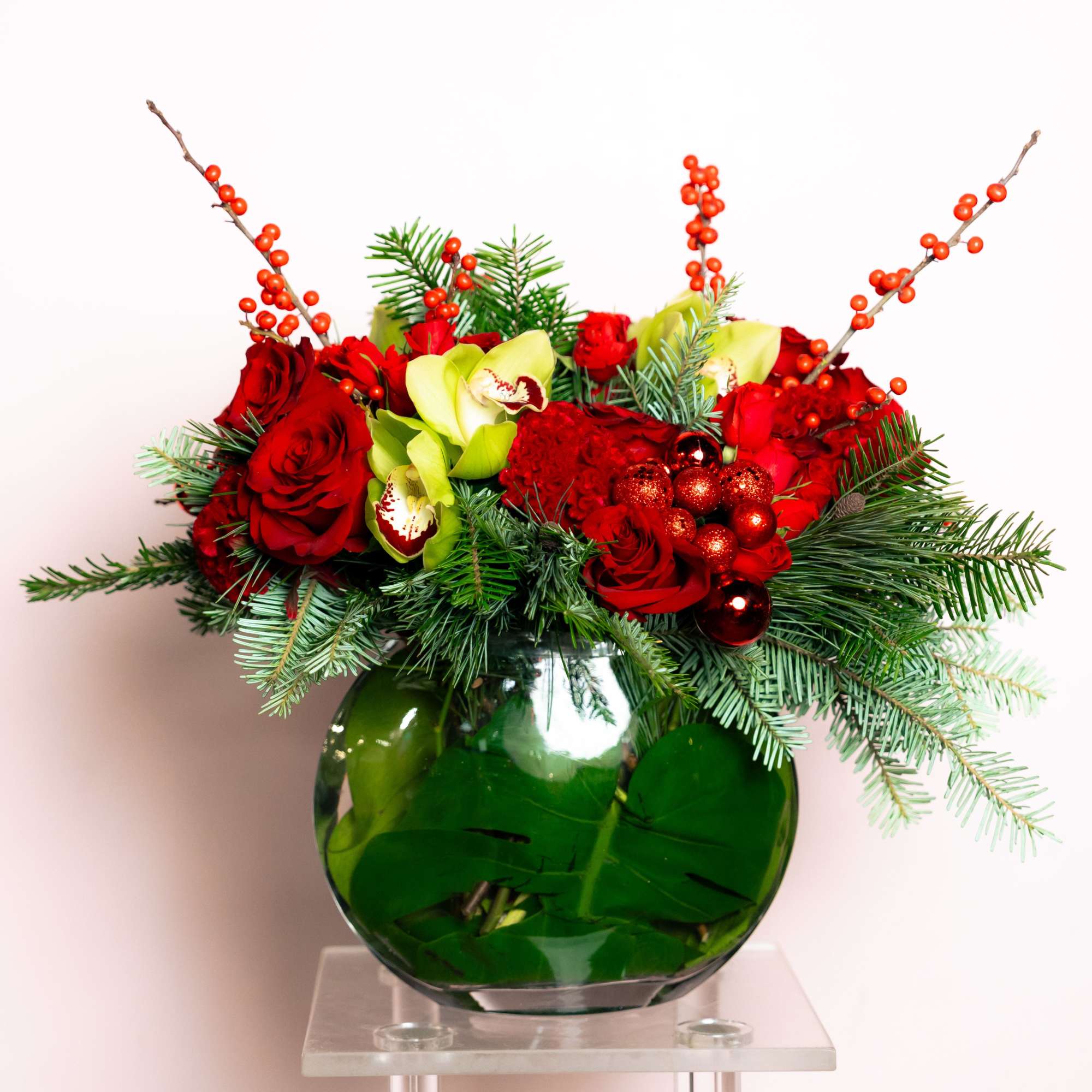 Berries, roses, orchids and holiday greens and ornaments in a fun circular