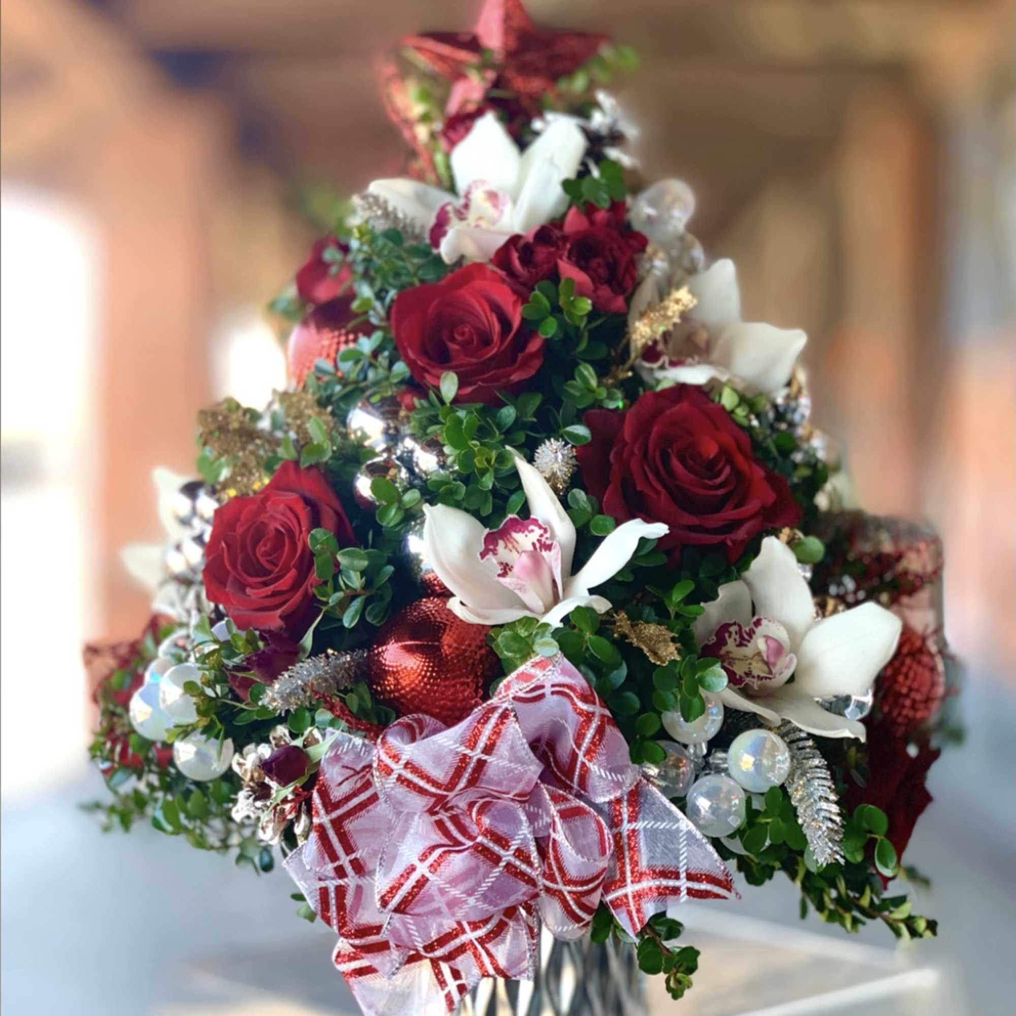 A Christmas tree made with boxwood green and assorted flowers like coffee