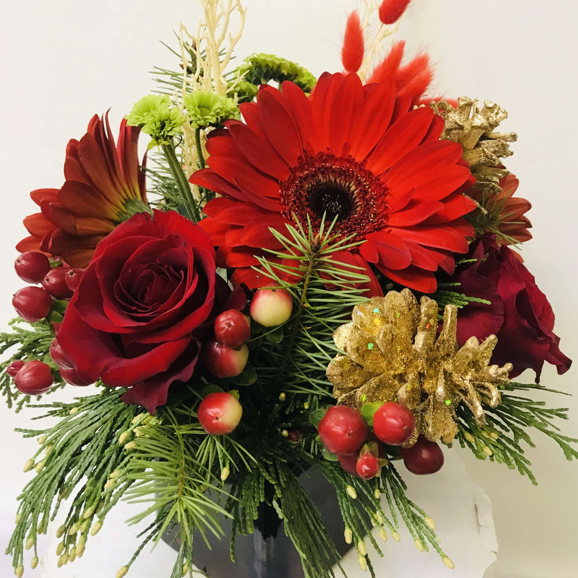 red glass vase with a Xmas greenery red Gerber, red roses and
