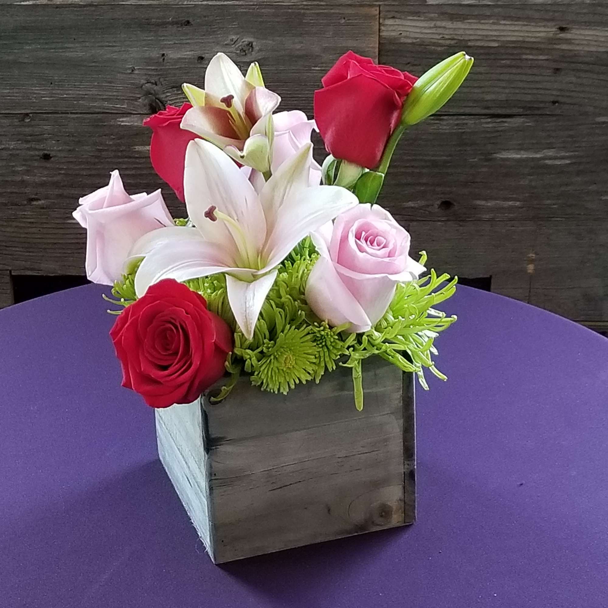 Lilies and roses on a bed of mums. Compact arrangement nice for